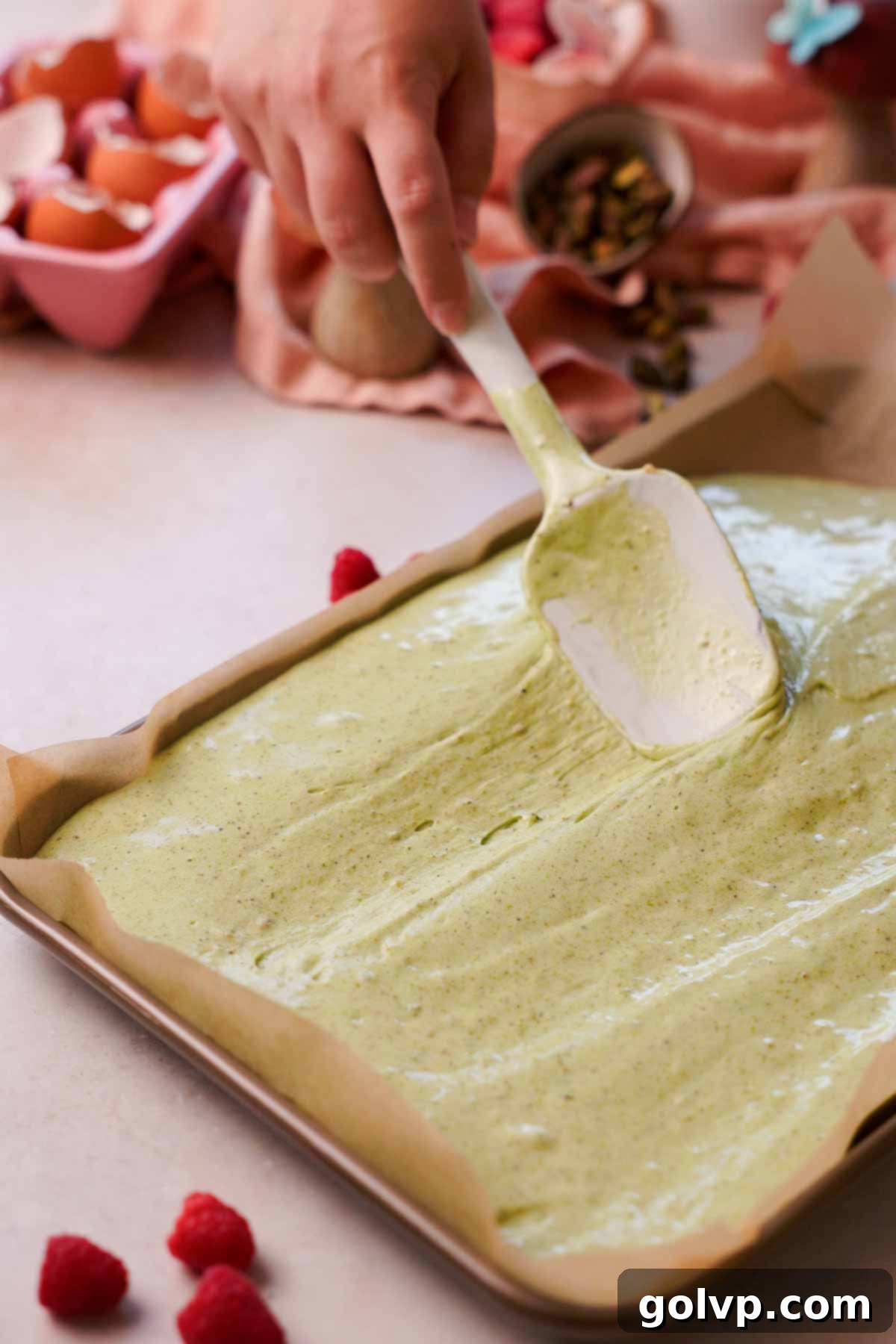 spreading pistachio spongecake batter on cake pan