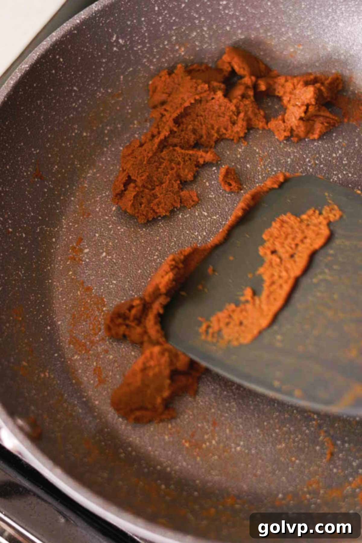 cooking pumpkin puree and spices in a nonstick pan with a spatula