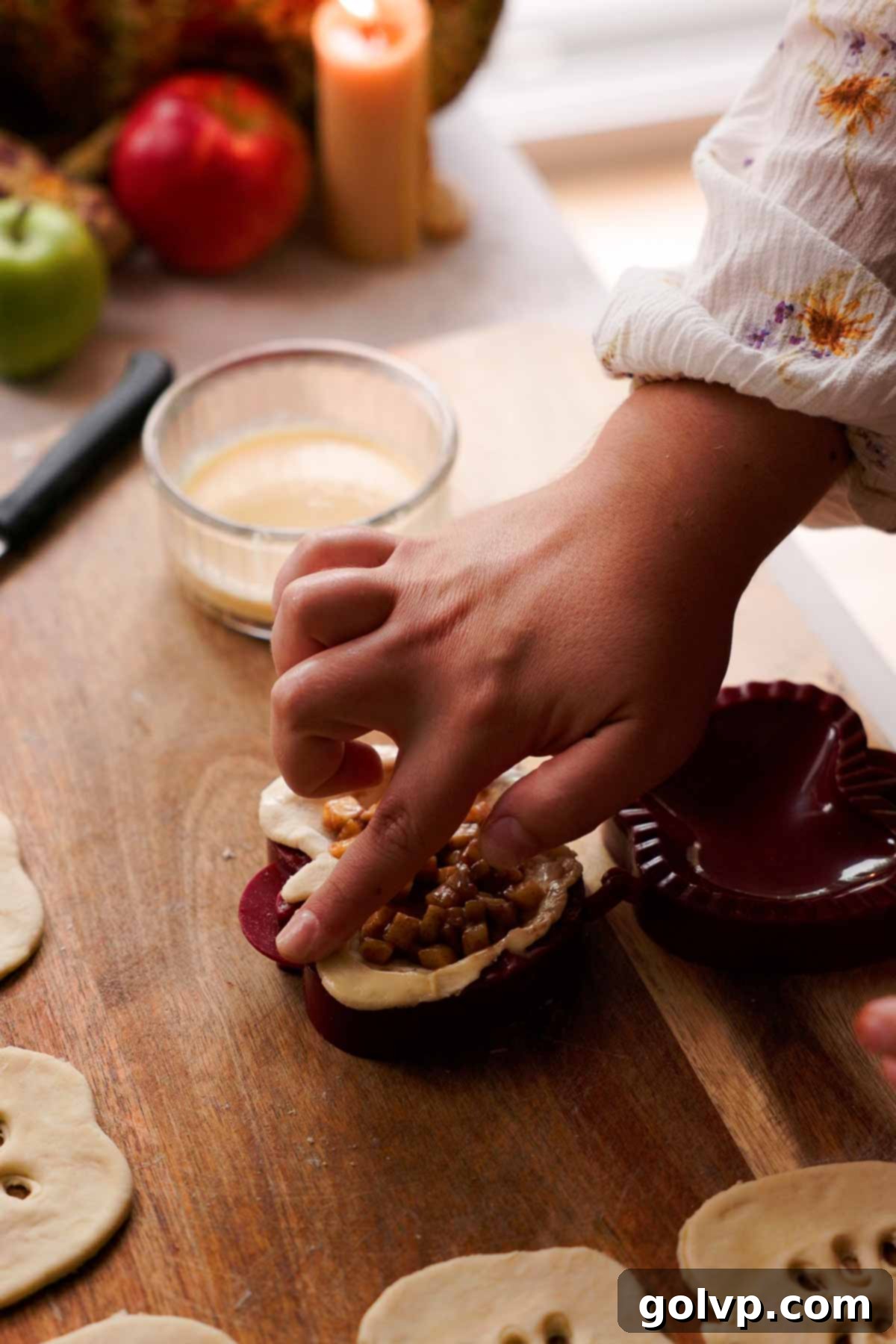 Rubbing eggwash over the edges of a pie pastry to seal it in a hand pie maker