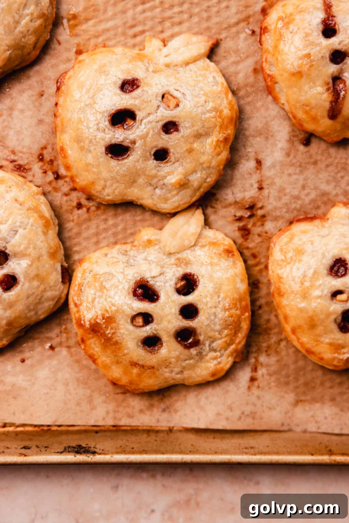 Freshly baked apple hand pies arranged on a parchment-lined baking sheet