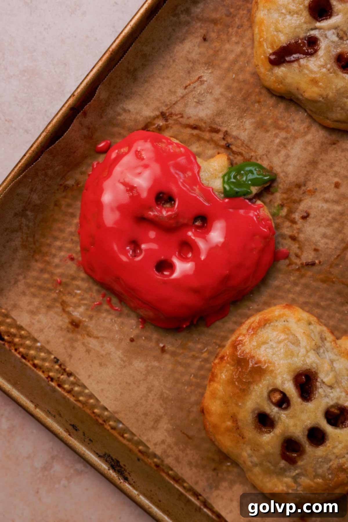 Glazed apple hand pie resting on parchment paper, showcasing its vibrant color