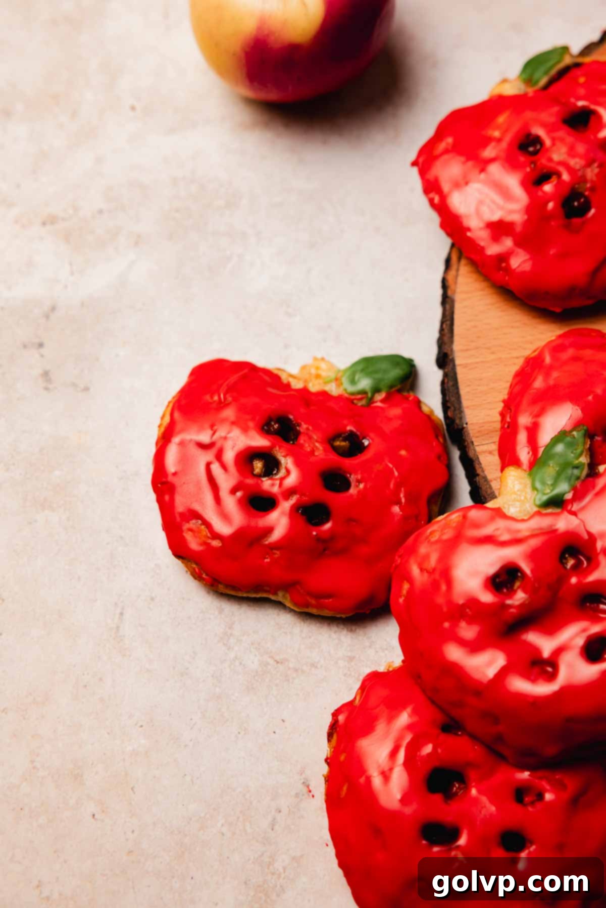 Collection of vibrant red apple-shaped hand pies on a rustic wooden table