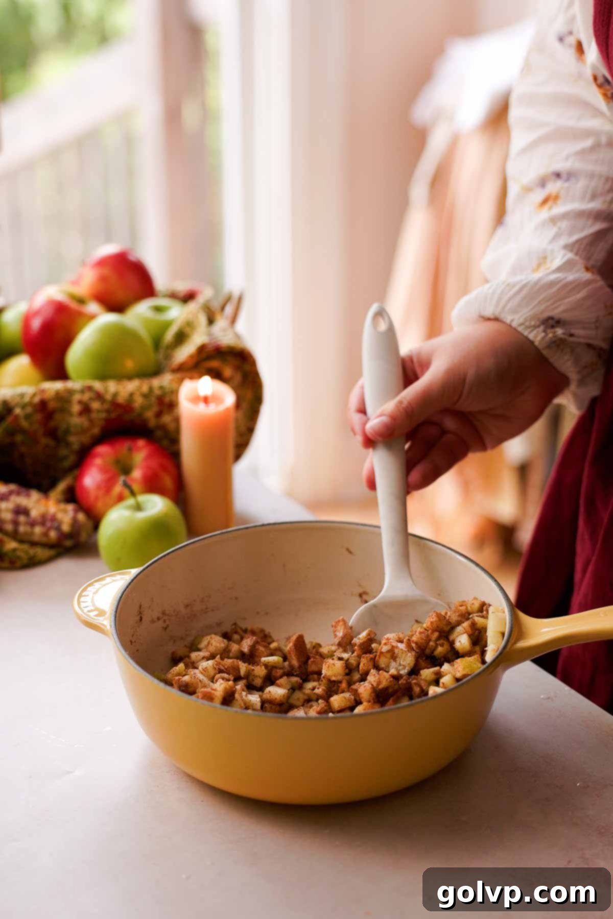 Stirring together a mixture of diced apples, brown sugar, and various spices in a pan for the pie filling