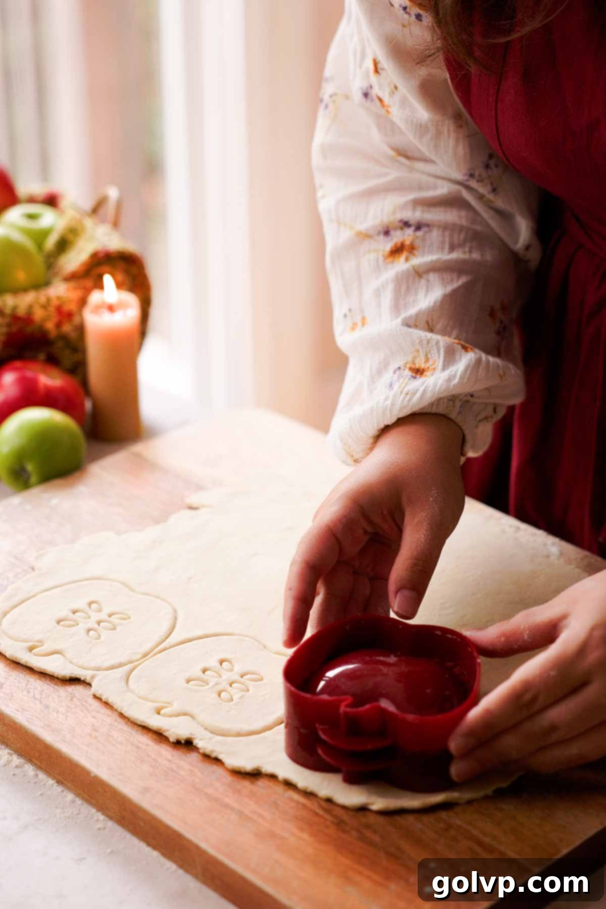 Cutting out apple shapes from pie crust dough using a cookie cutter