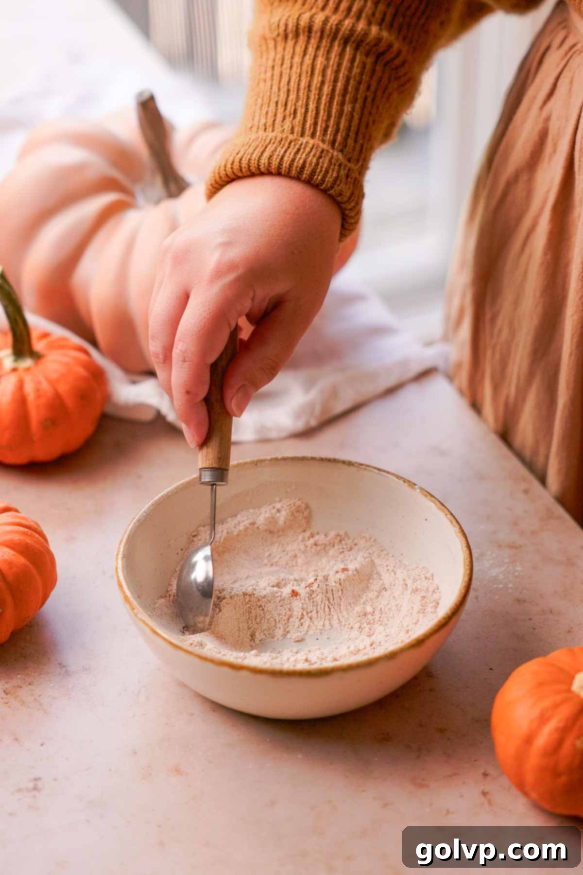Autumn Pumpkin Streusel Cream Cheese Delight 11 stirring flour, sugar, and cinnamon in a bowl with a measuring spoon