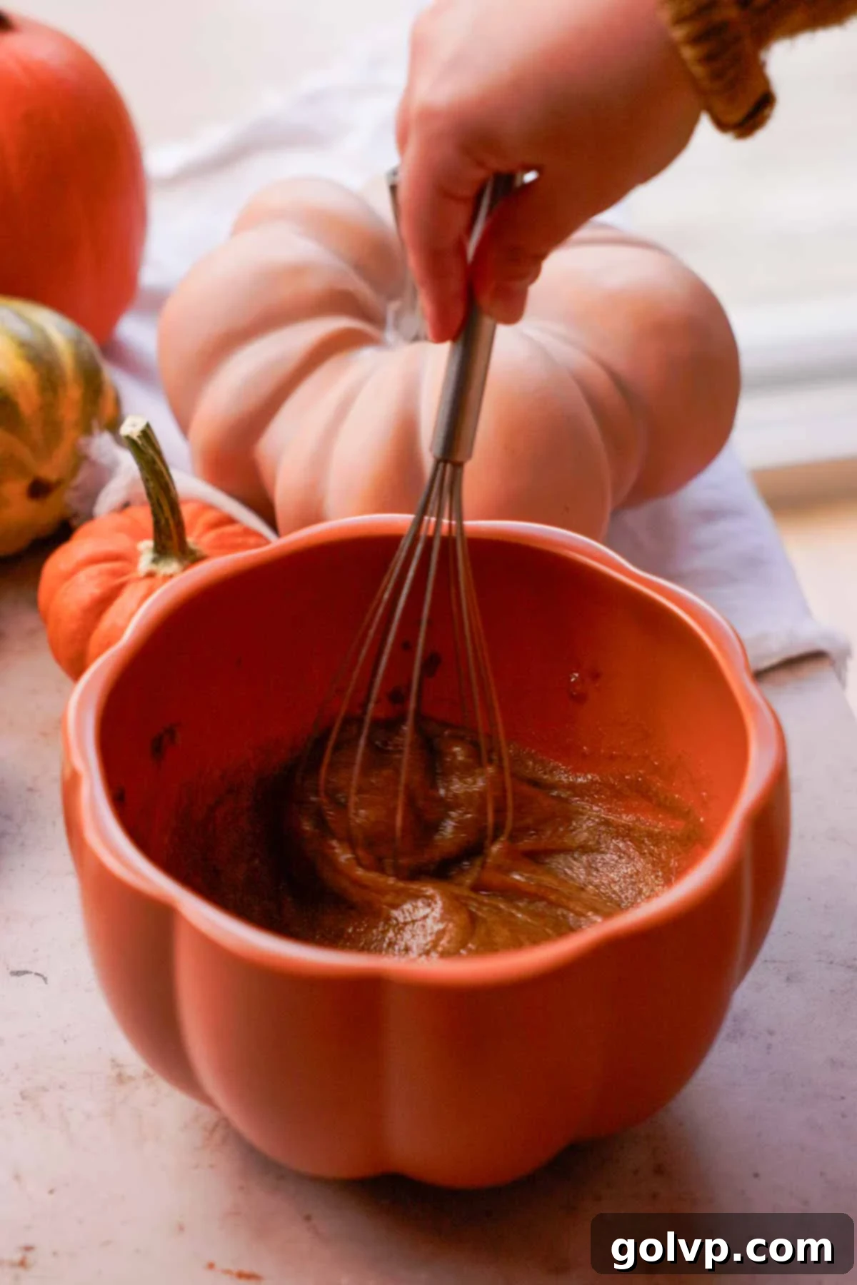 Autumn Pumpkin Streusel Cream Cheese Delight 5 whisking eggs and brown sugar with a wire whisk in a pumpkin bowl