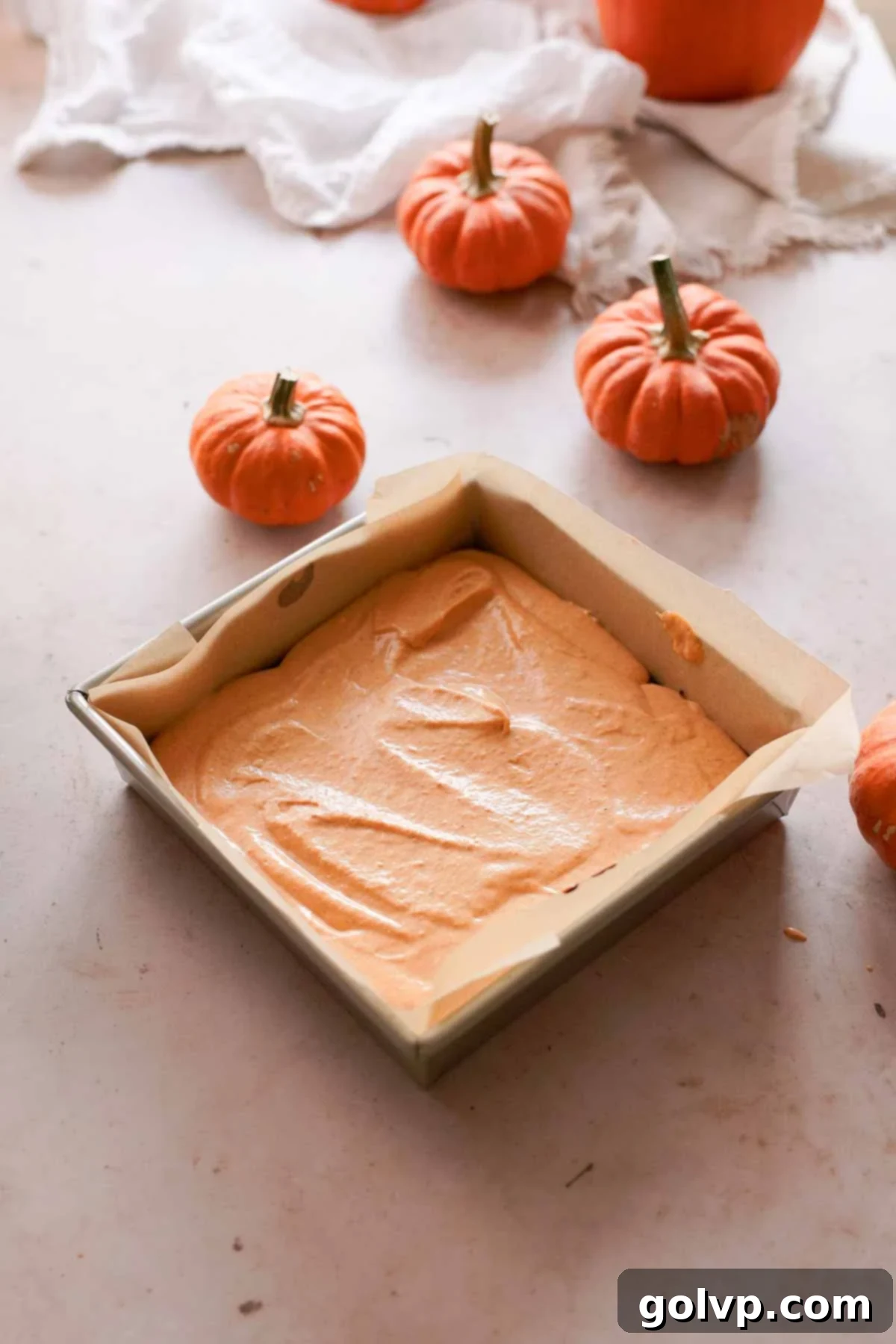 layer of pumpkin cheesecake batter in brownie pan