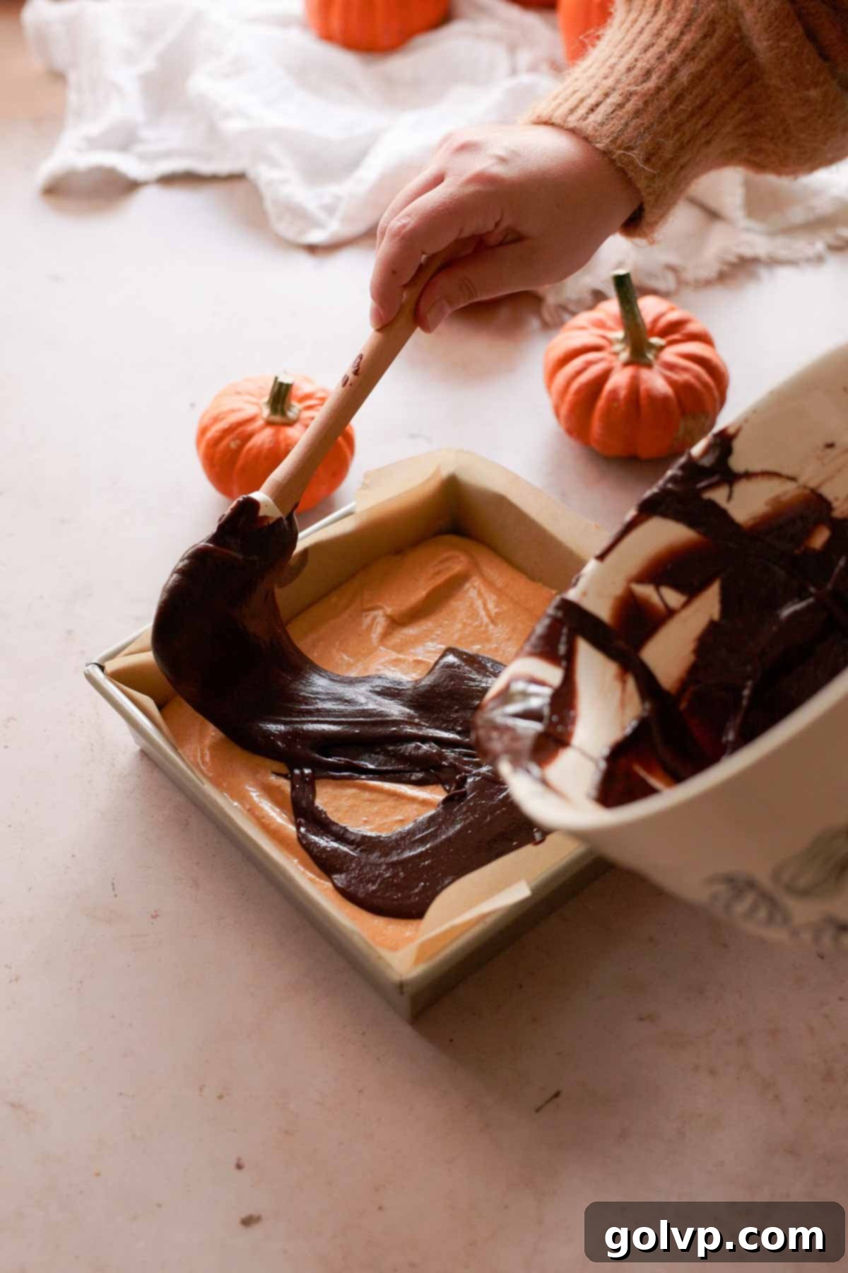 carefully layering brownie batter onto cheesecake batter in baking pan