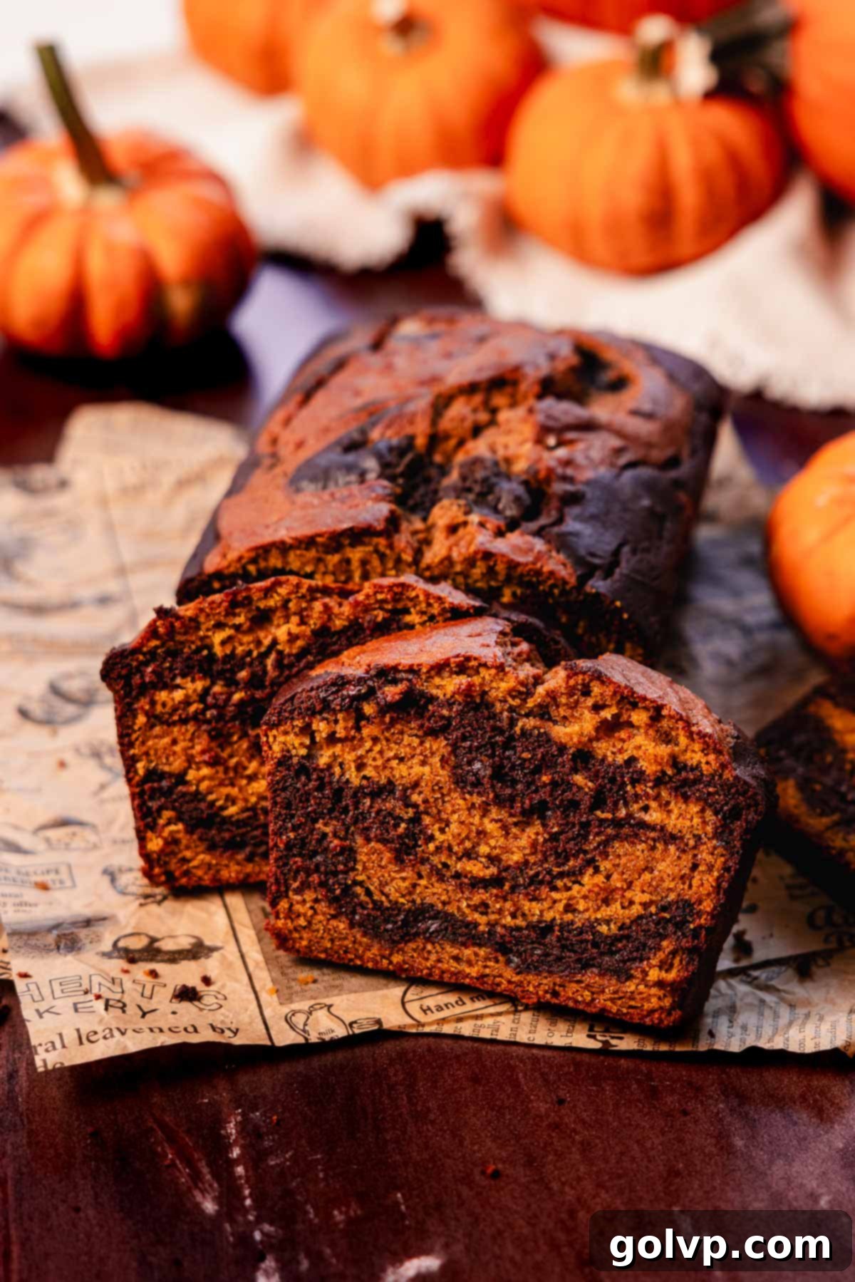 slices of pumpkin and chocolate swirled bread on printed parchment paper, highlighting the rich colors