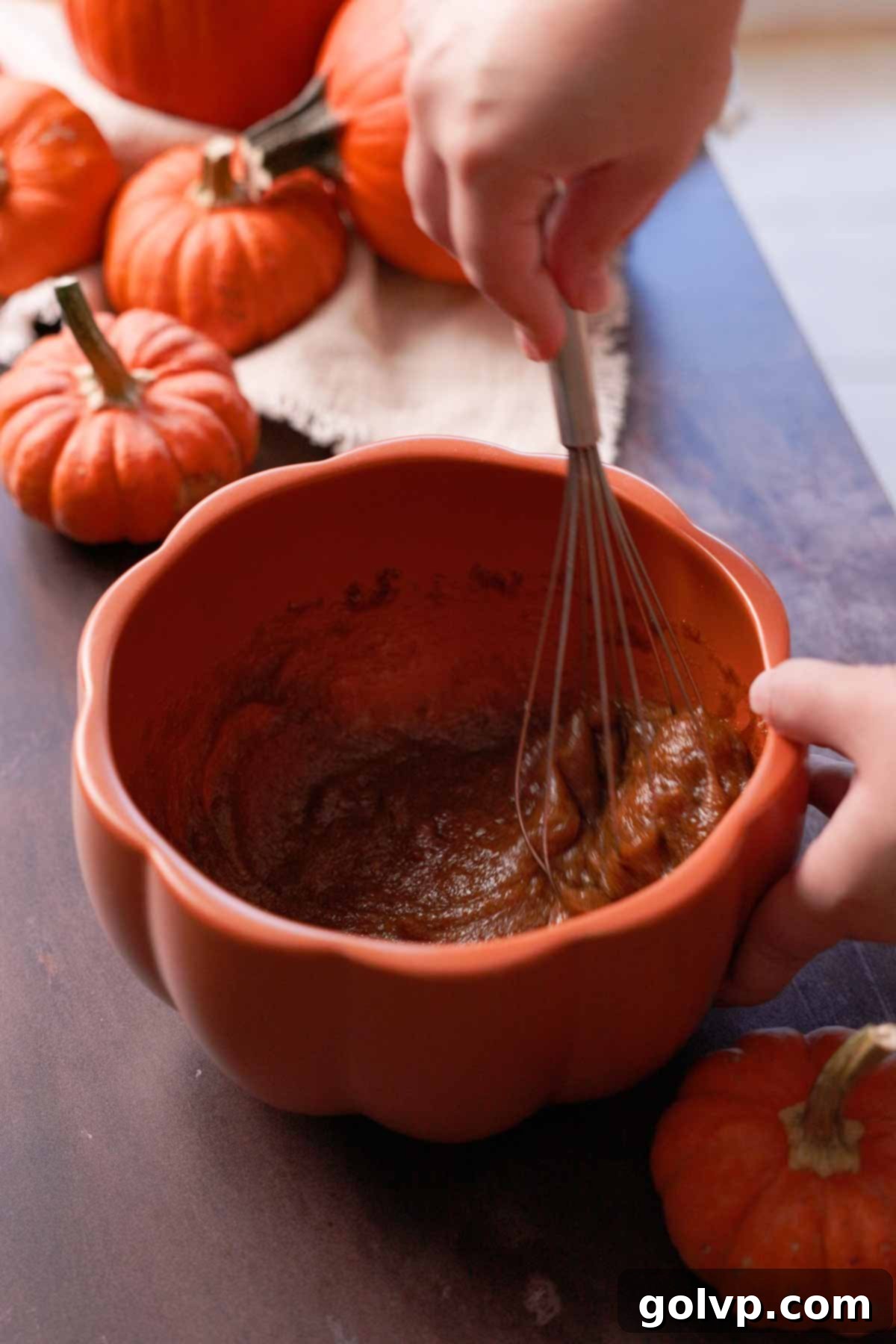 whisking eggs and brown sugar with a wire whisk in a pumpkin shaped bowl until light and foamy