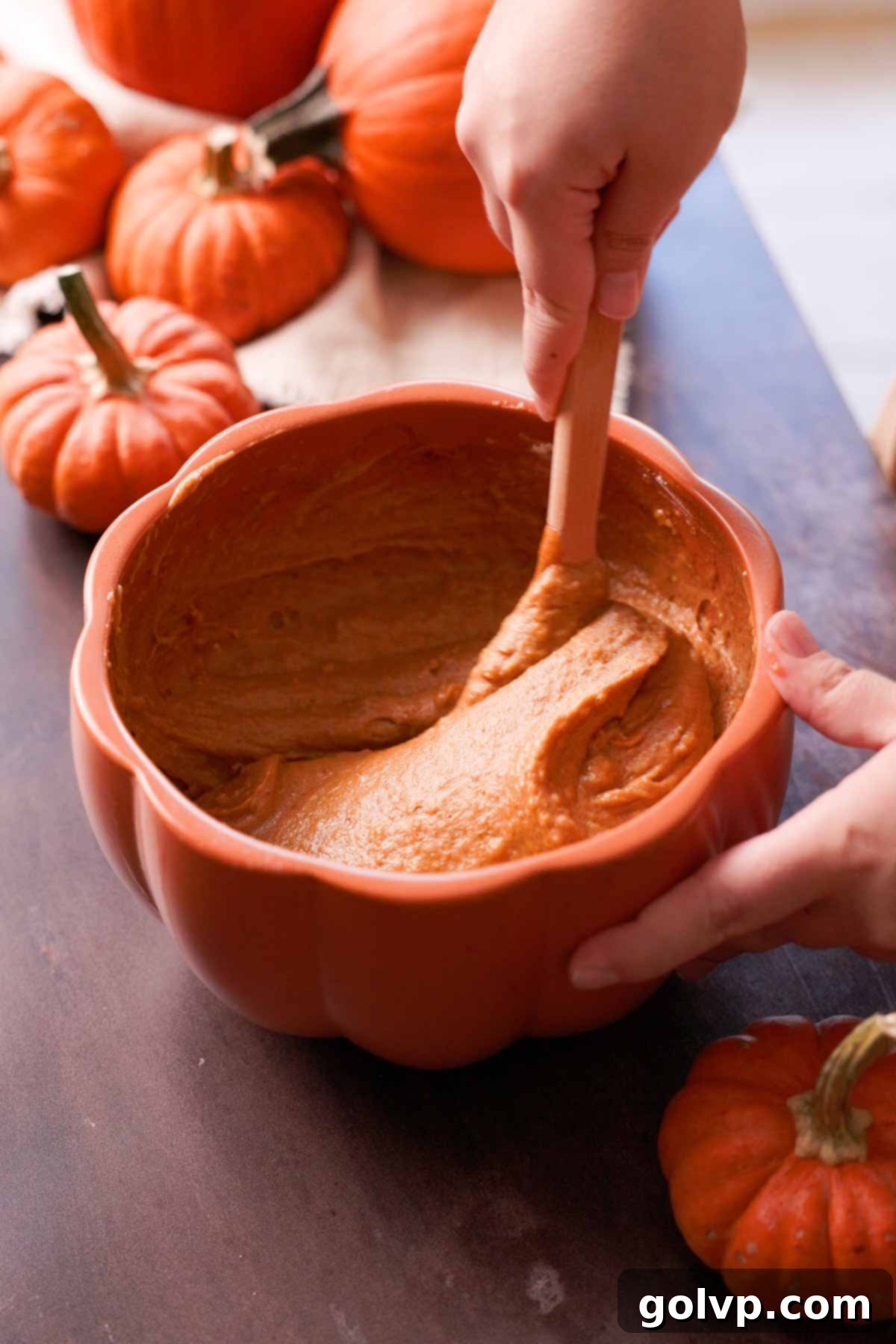 gently stirring pumpkin bread batter with a silicone spatula after adding dry ingredients