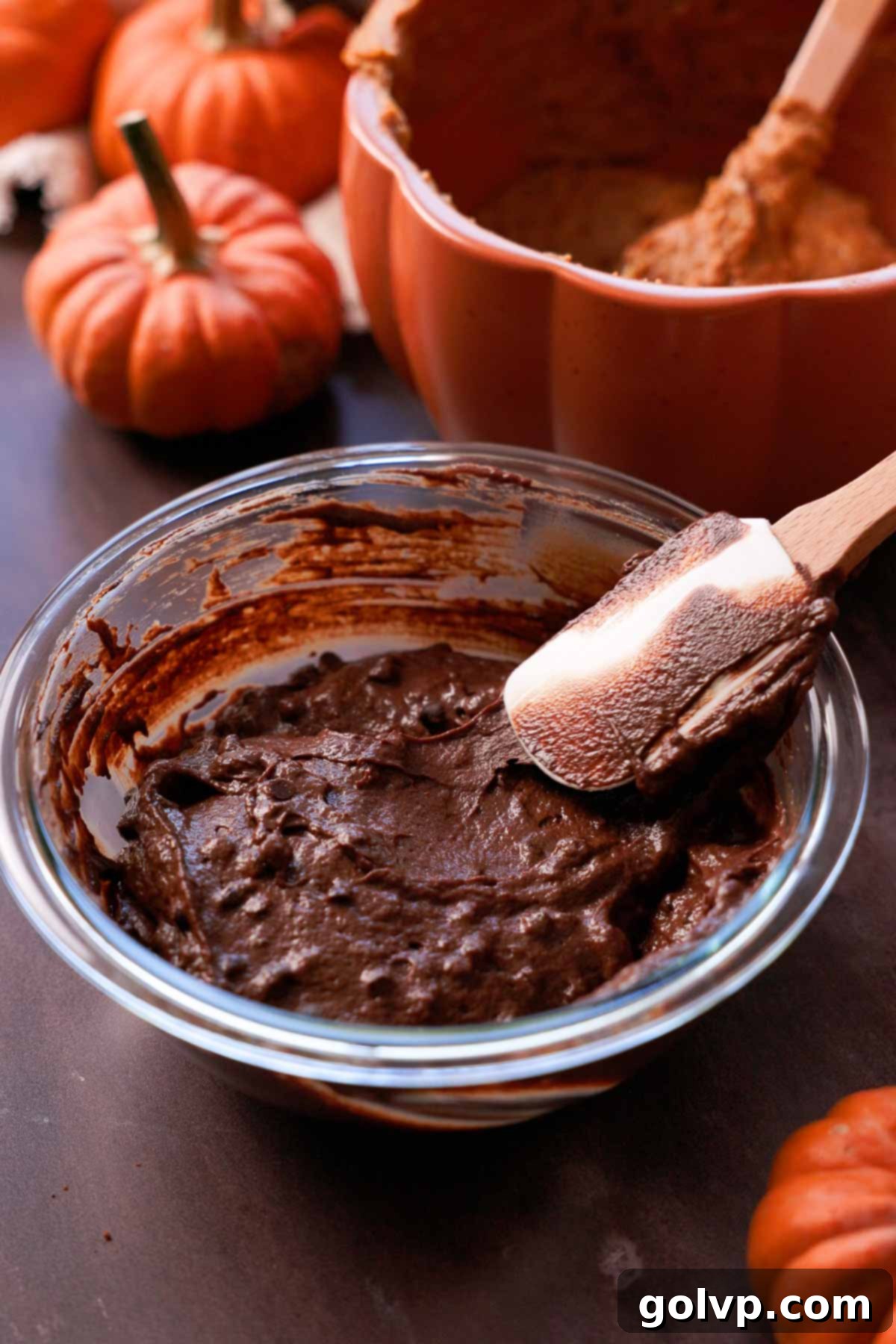 folding mini chocolate chips into chocolate pumpkin bread batter with a spatula