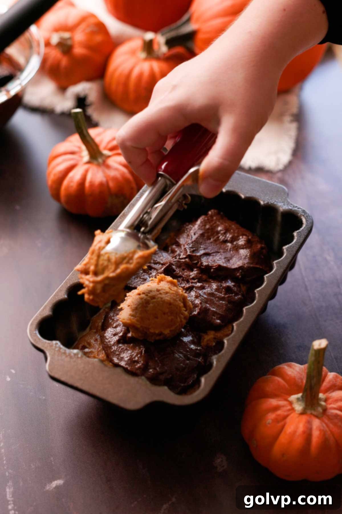 layering pumpkin and chocolate batter alternately into a loaf pan to create a swirl effect