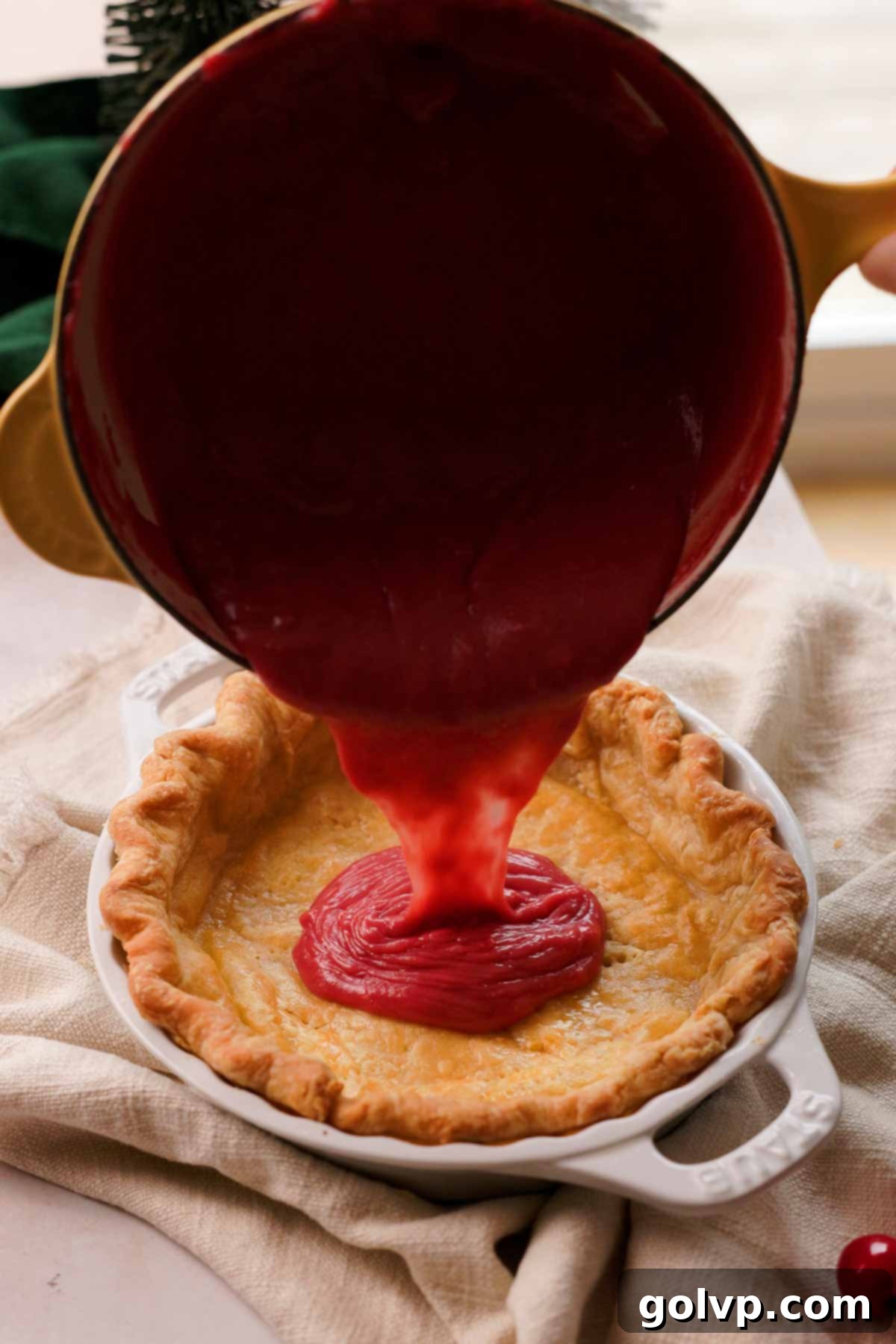pouring tart cherry curd into baked pie crust