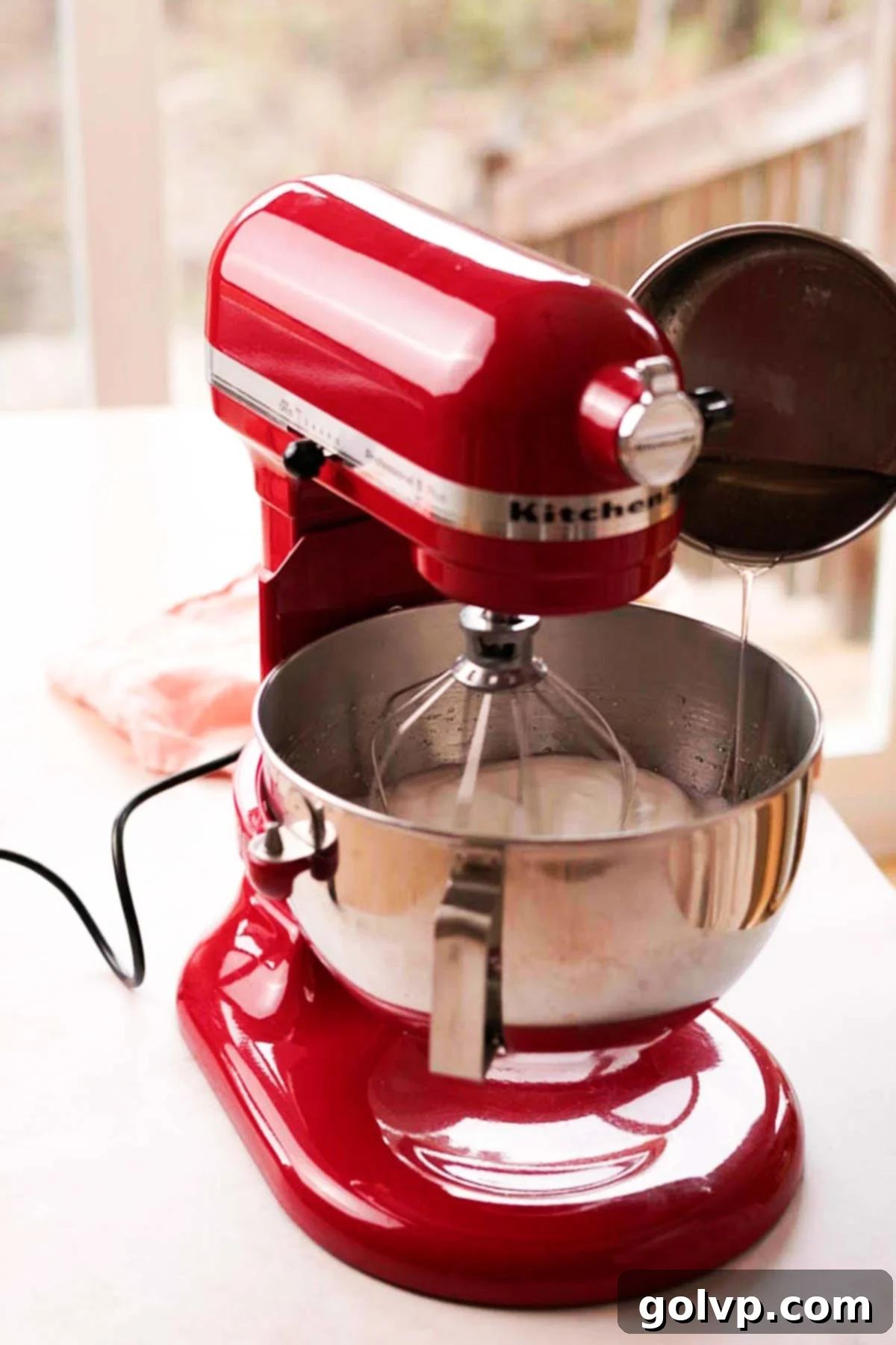 pouring hot sugar syrup into a stand mixer bowl to make italian meringue