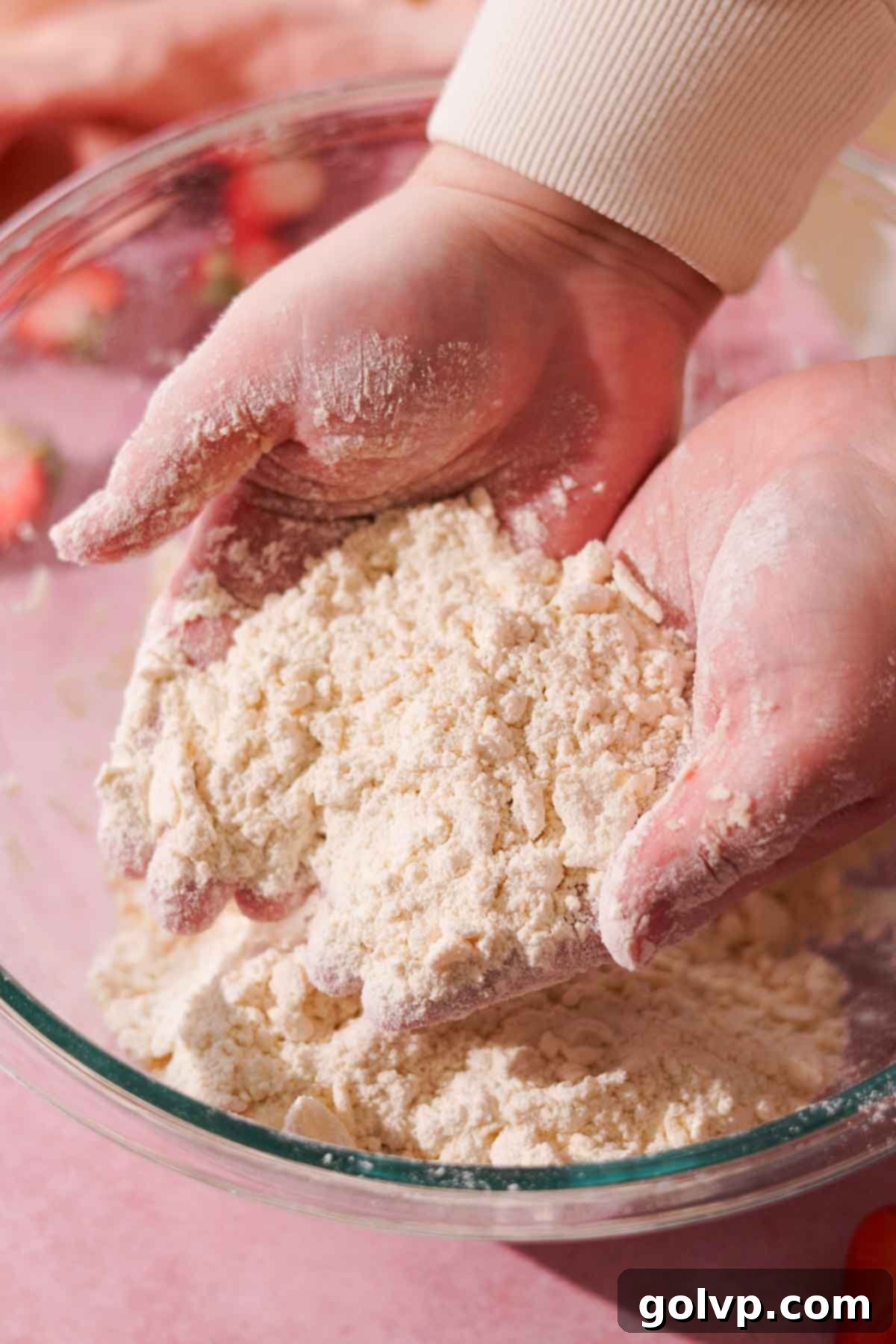 holding butter and flour in hands on top of glass bowl to show texture