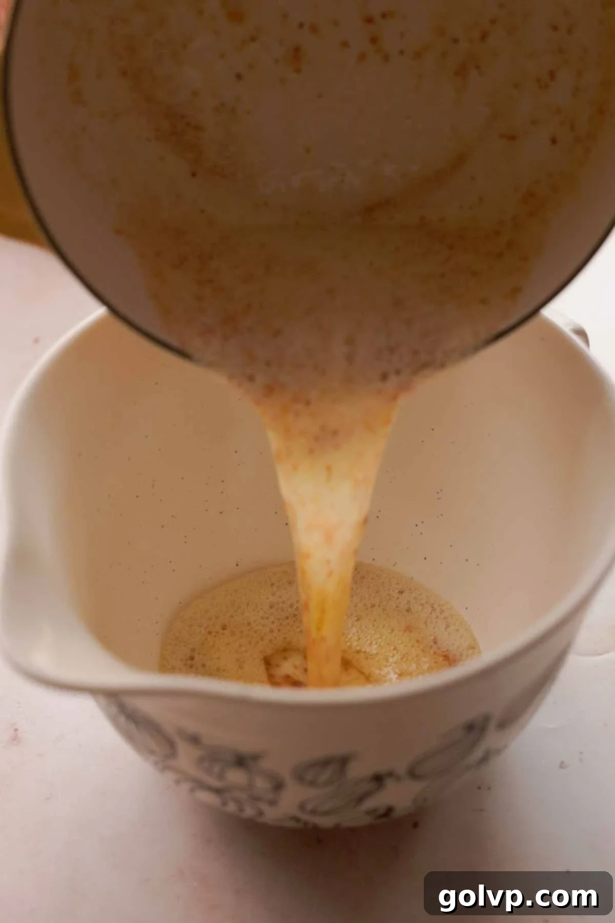 pouring brown butter with milk powder into large mixing bowl