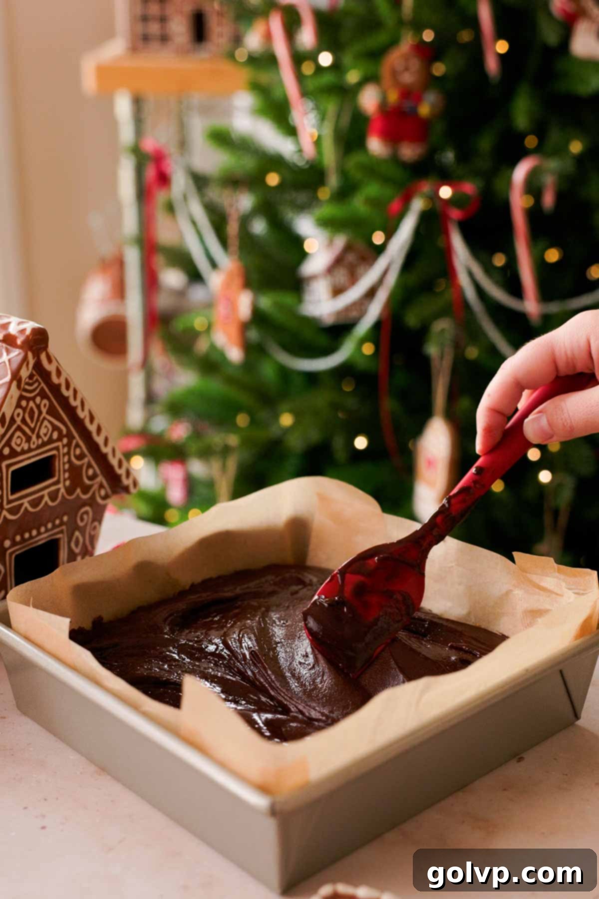 spreading brownie batter into parchment paper lined baking pan
