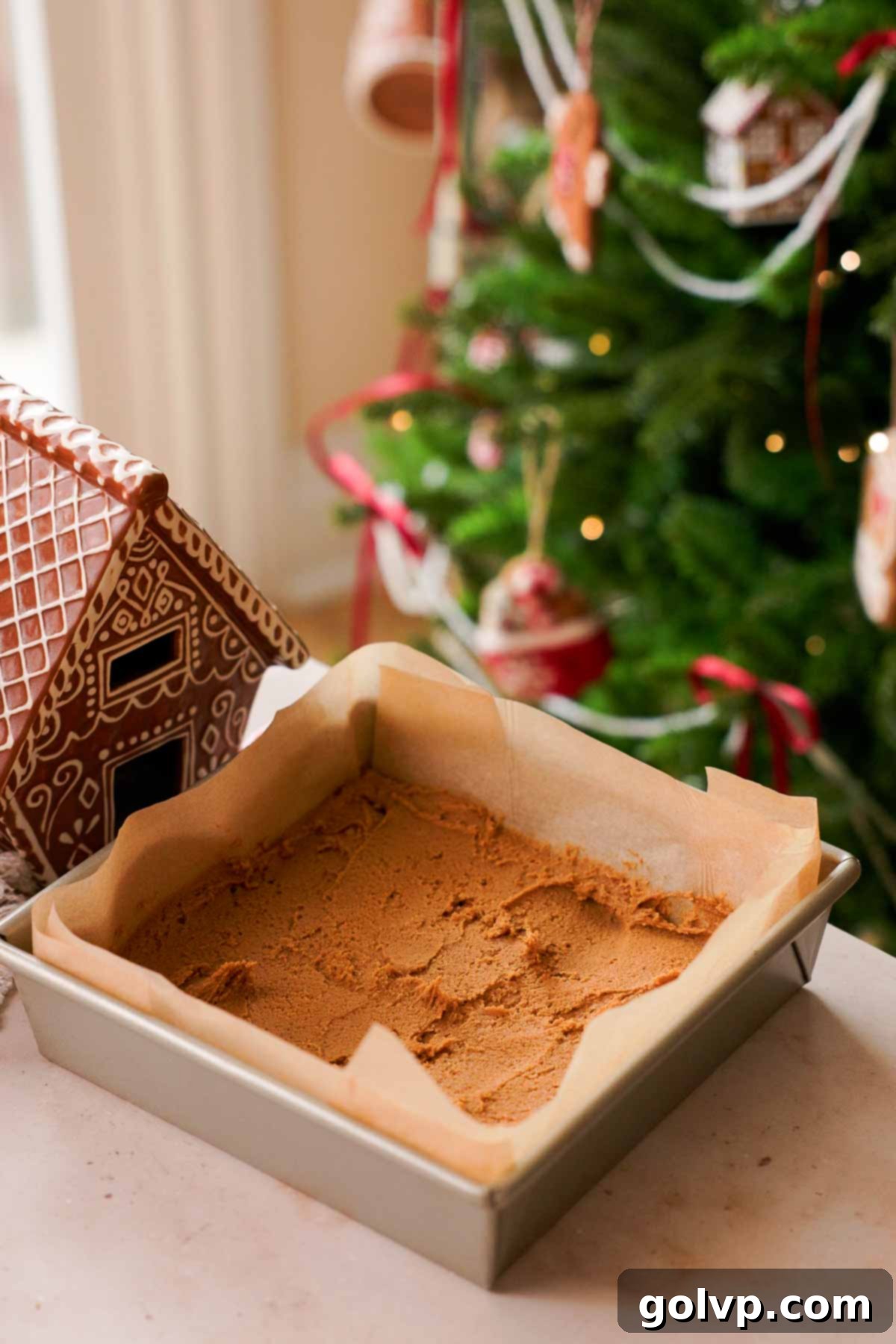 spreading gingerbread cookie dough in parchment lined baking pan