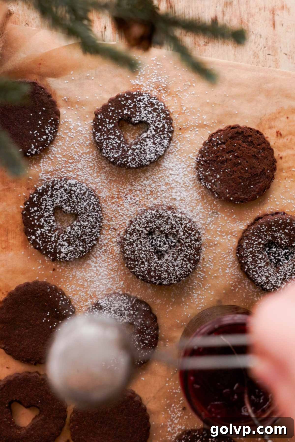 dusting chocolate almond linzer cookies with powdered sugar