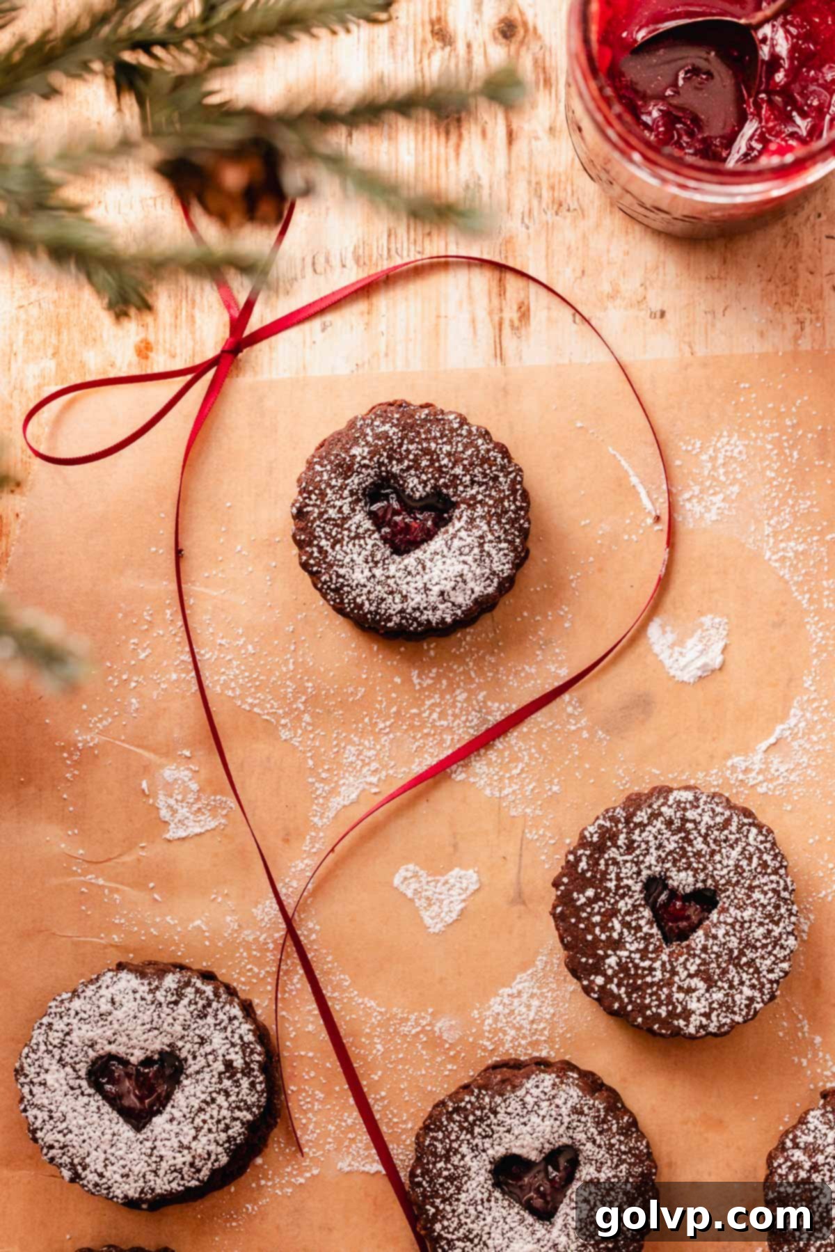 chocolate cherry linzer cookie on parchment paper with a bow