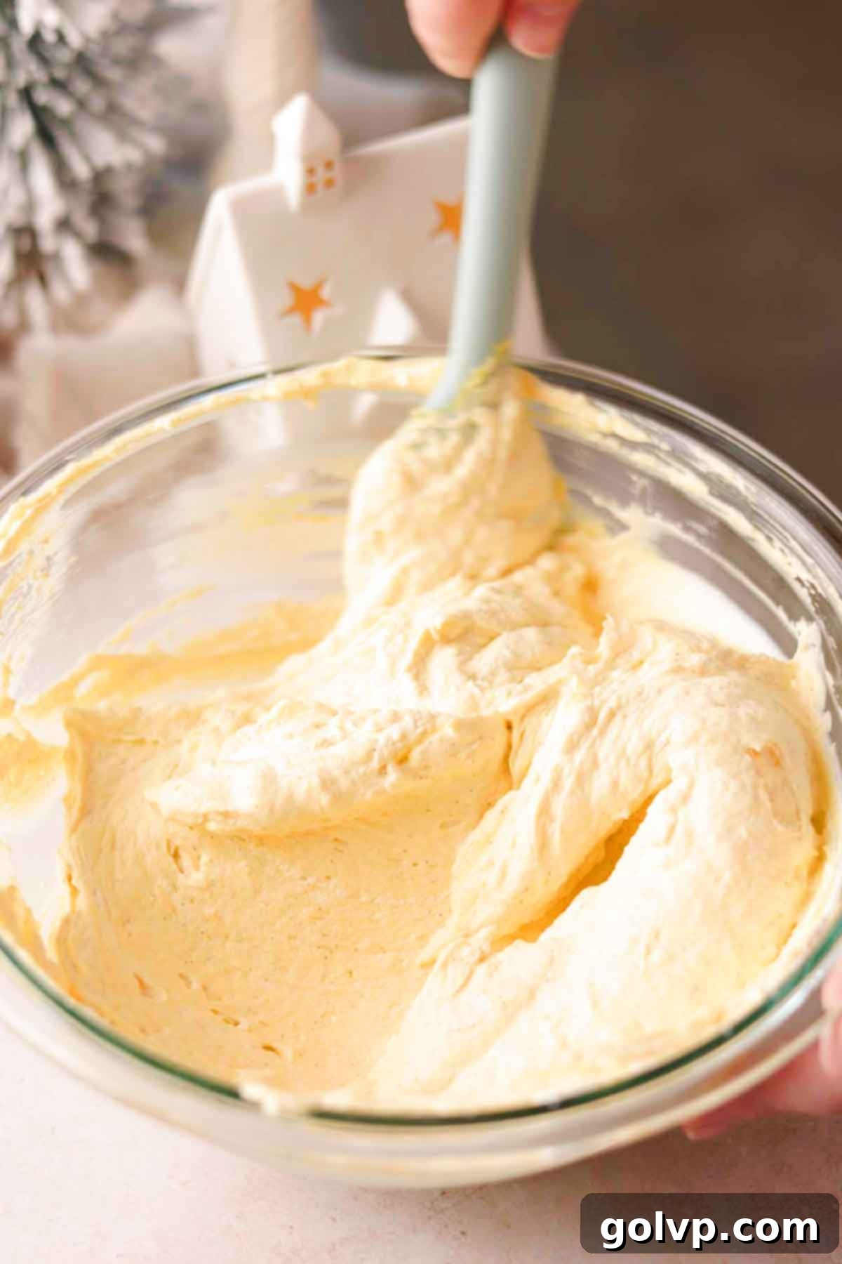 Gently folding vibrant mango puree into the creamy mascarpone whipped cream with a spatula.