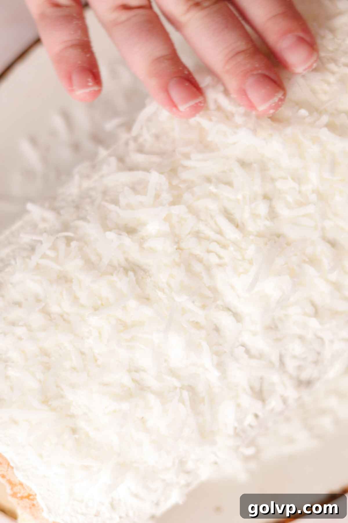 Covering the mango Swiss roll cake generously with sweetened flaked coconut.