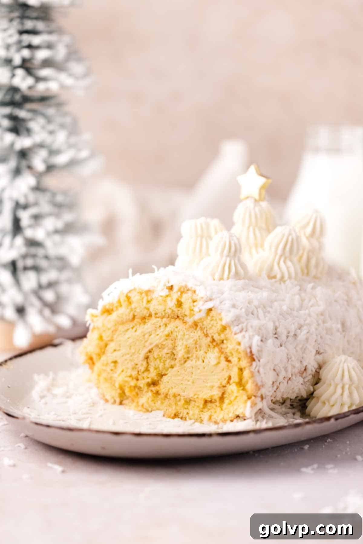 Mango coconut cake with shredded coconut outside and festive piped Christmas trees on top, ready for the holidays.