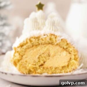 A festive Mango Coconut Swiss Roll Cake, showcasing its creamy mascarpone filling and a beautiful swirl, adorned with coconut and small piped trees.
