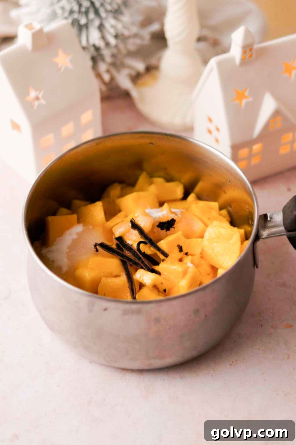 Diced mango, sugar, vanilla bean, and water simmering in a saucepan for a homemade mango puree.