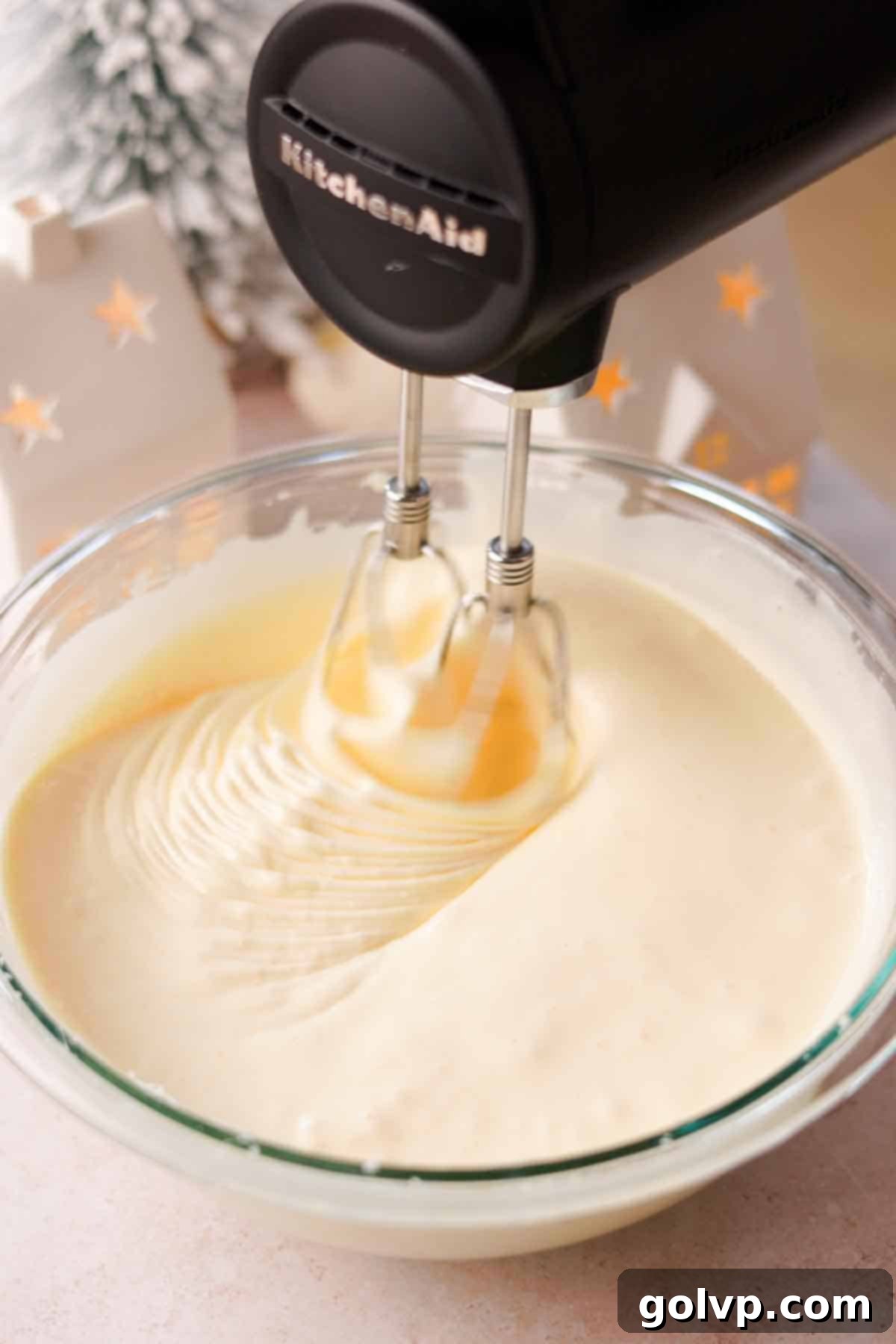 Eggs and sugar being beaten in a stand mixer until thick, pale, and fluffy for a light sponge cake.