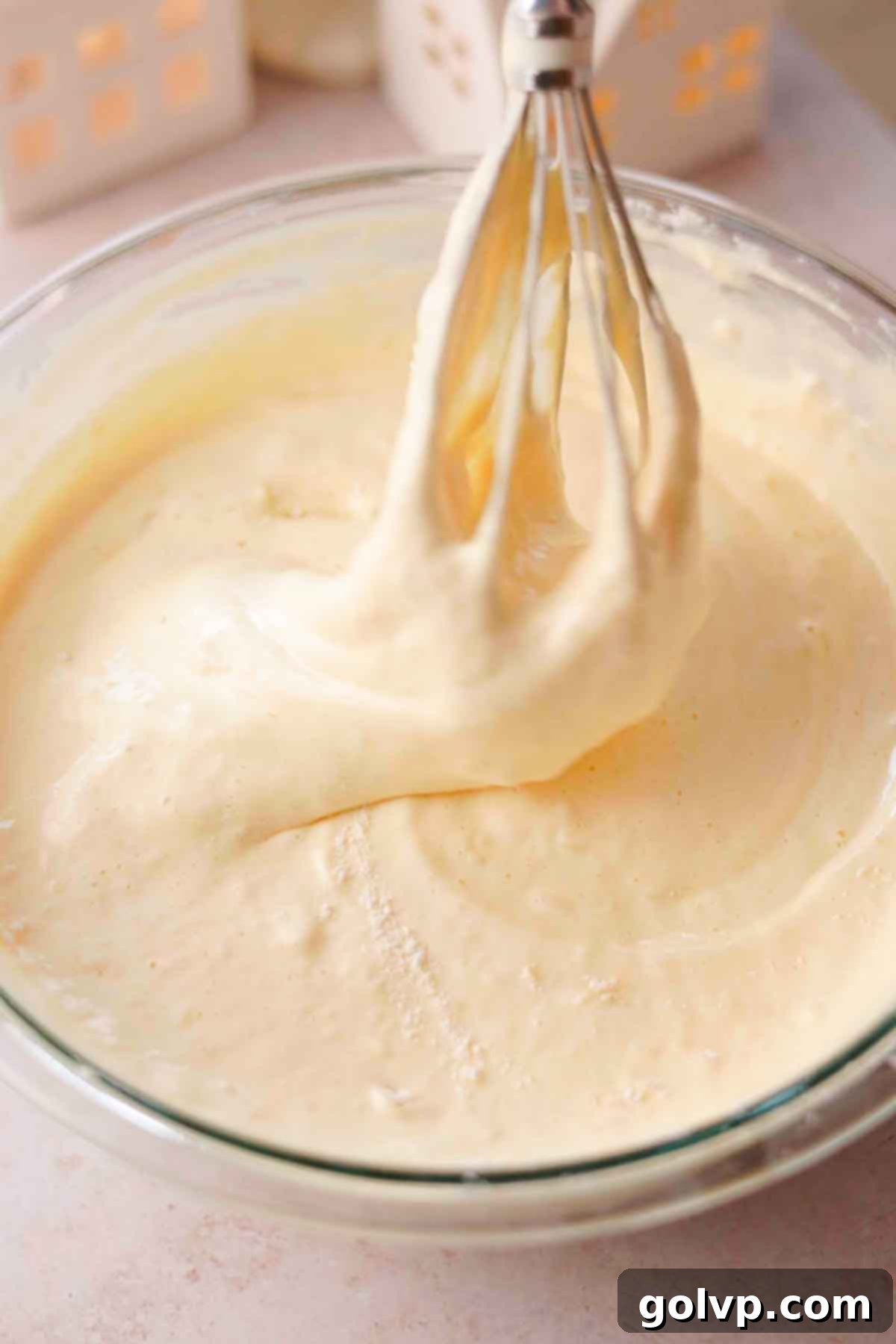 Gently folding dry ingredients into whipped egg batter with a whisk for sponge cake.