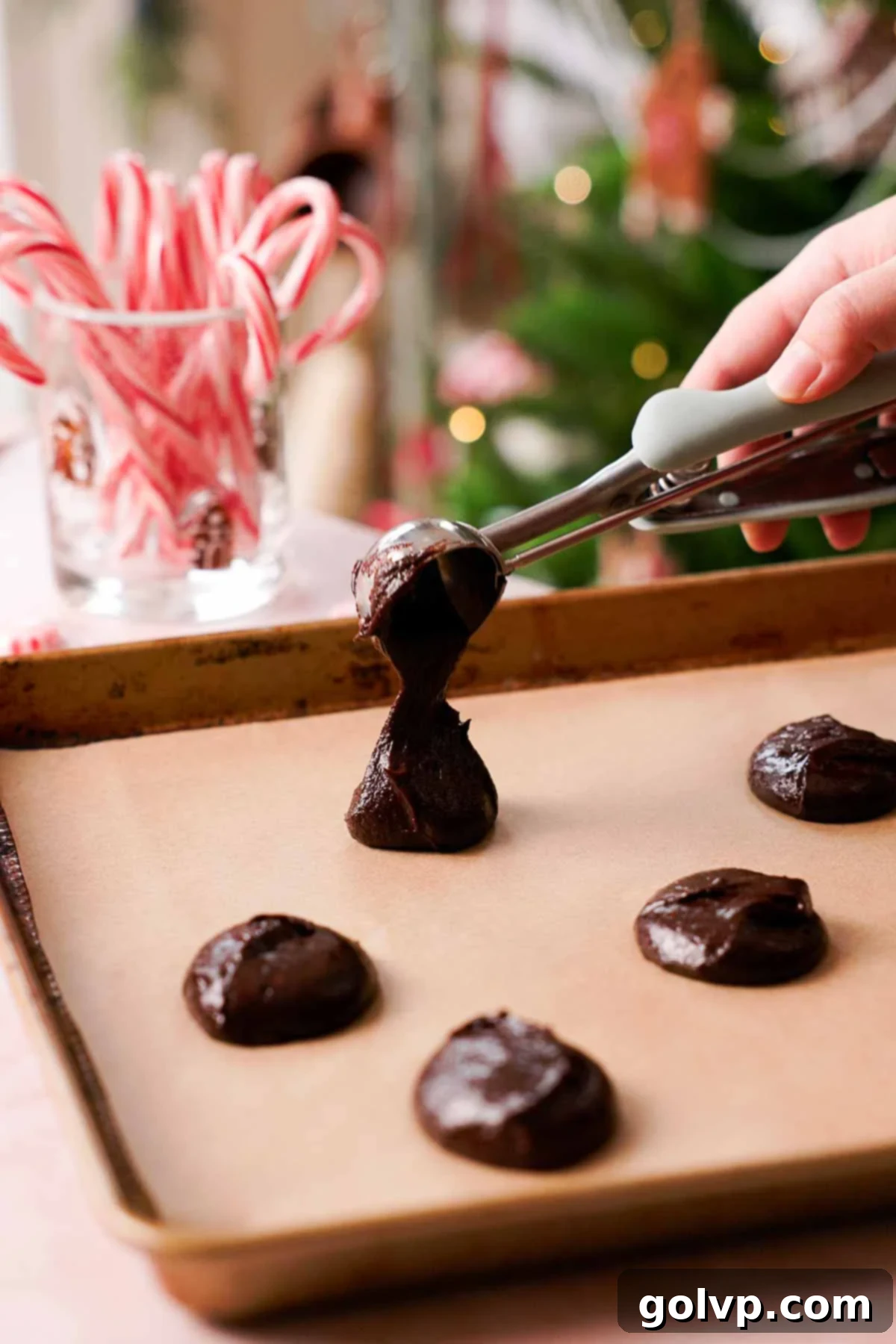 scooping peppermint brownie cookie dough onto parchment paper-lined baking sheet