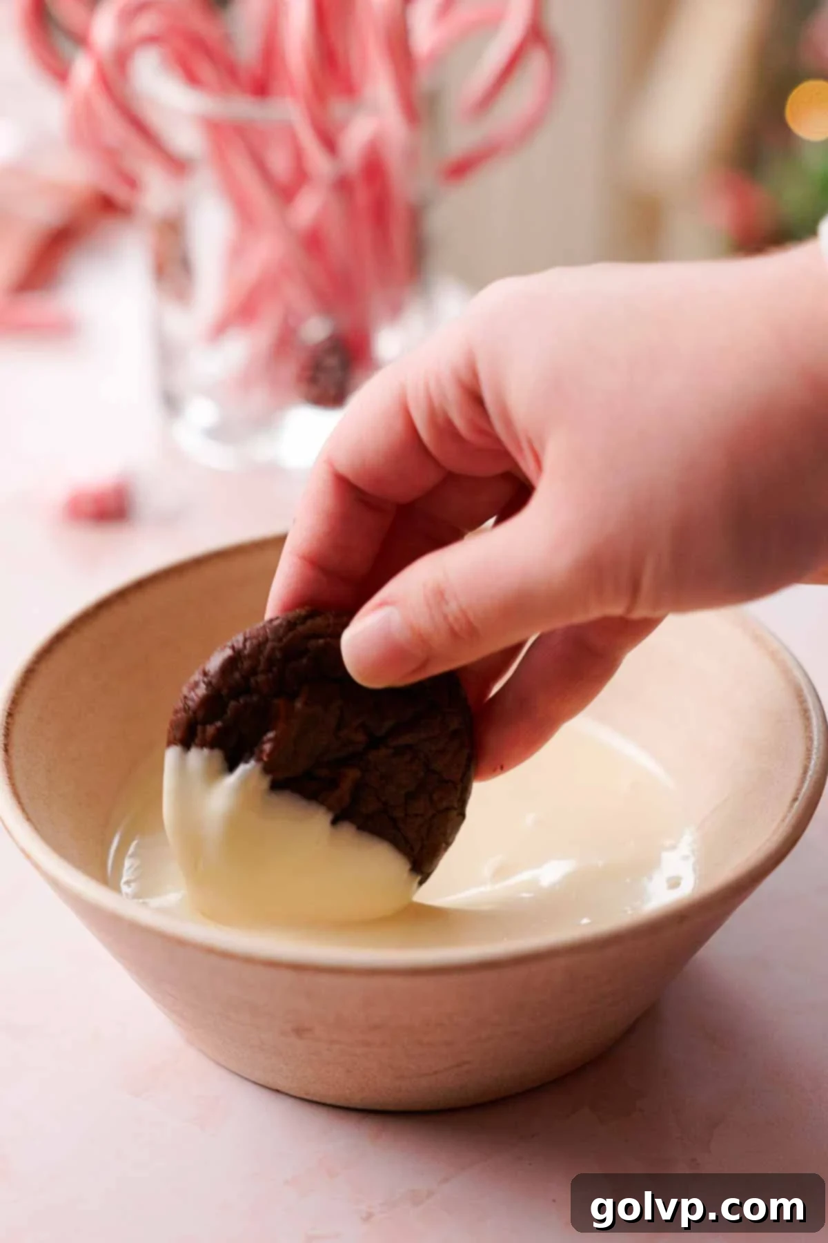 dipping peppermint brownie cookies into melted white chocolate