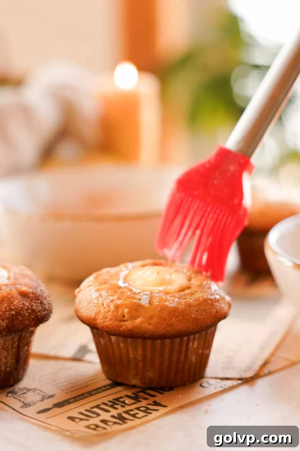 Brushing the tops of warm apple cider muffins with a butter and apple cider mixture