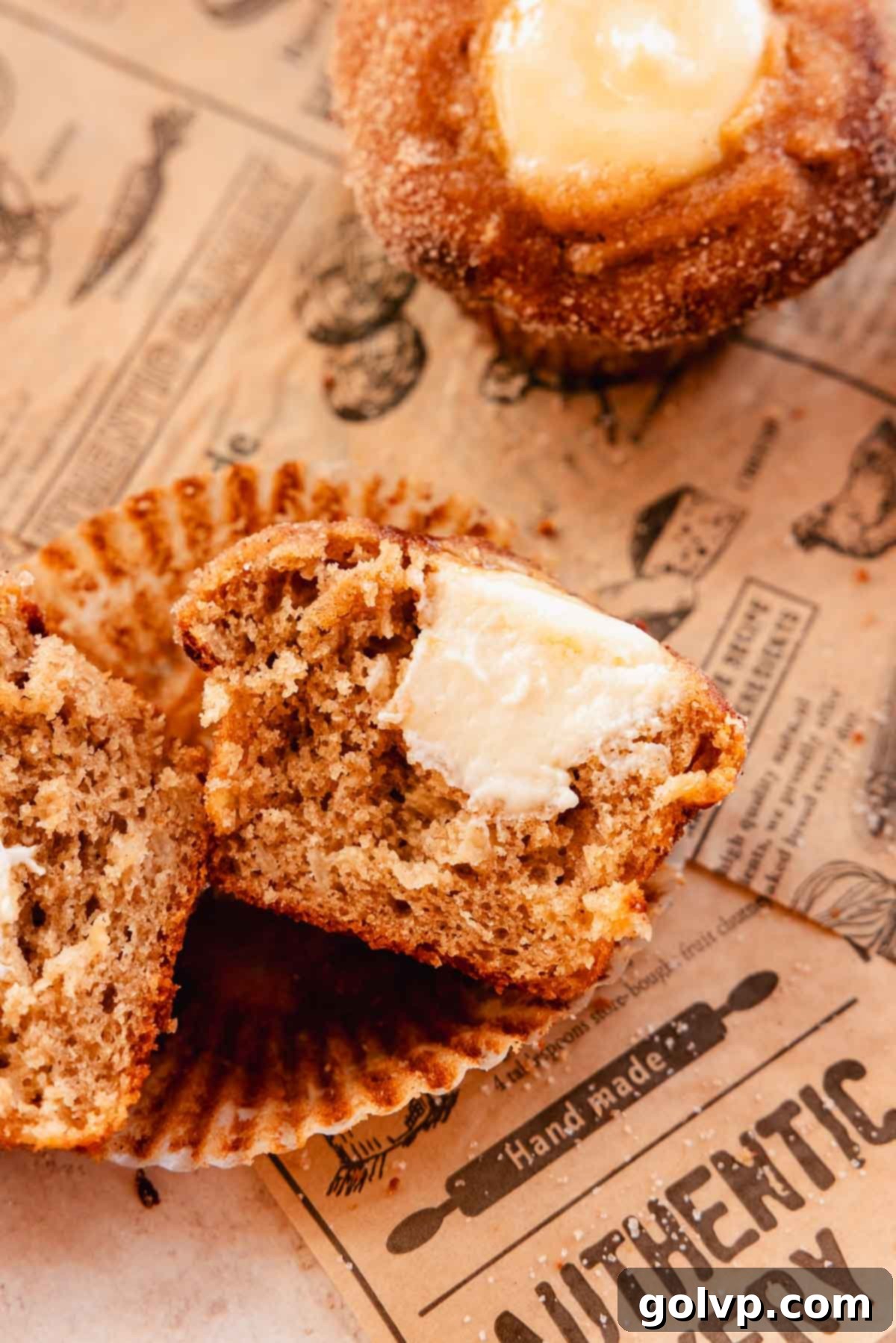 Apple cider muffin cut in half to clearly show the creamy cream cheese filling inside