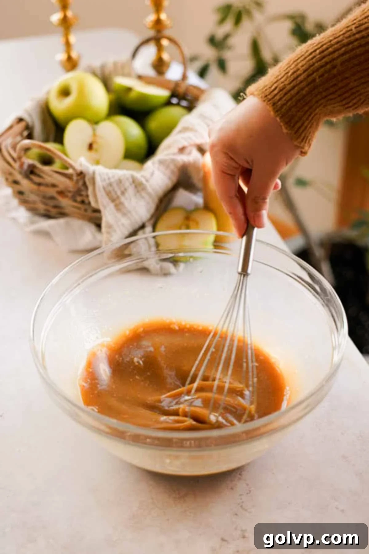 Whisking apple cider wet ingredients in a large bowl with a wire whisk for muffin batter