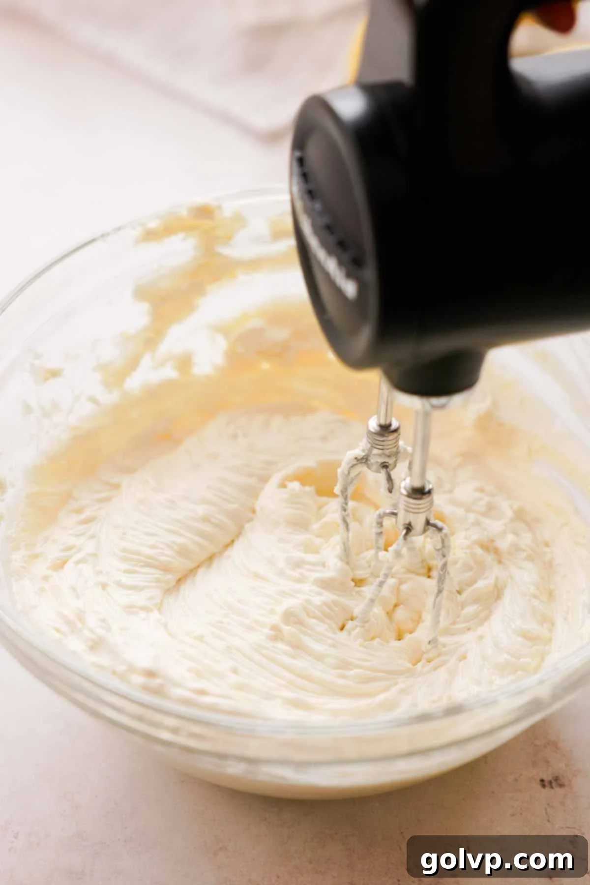 Lemon Poppy Seed Cheesecake Perfection 10 using handheld mixer to mix cream cheese and sugar together in a bowl