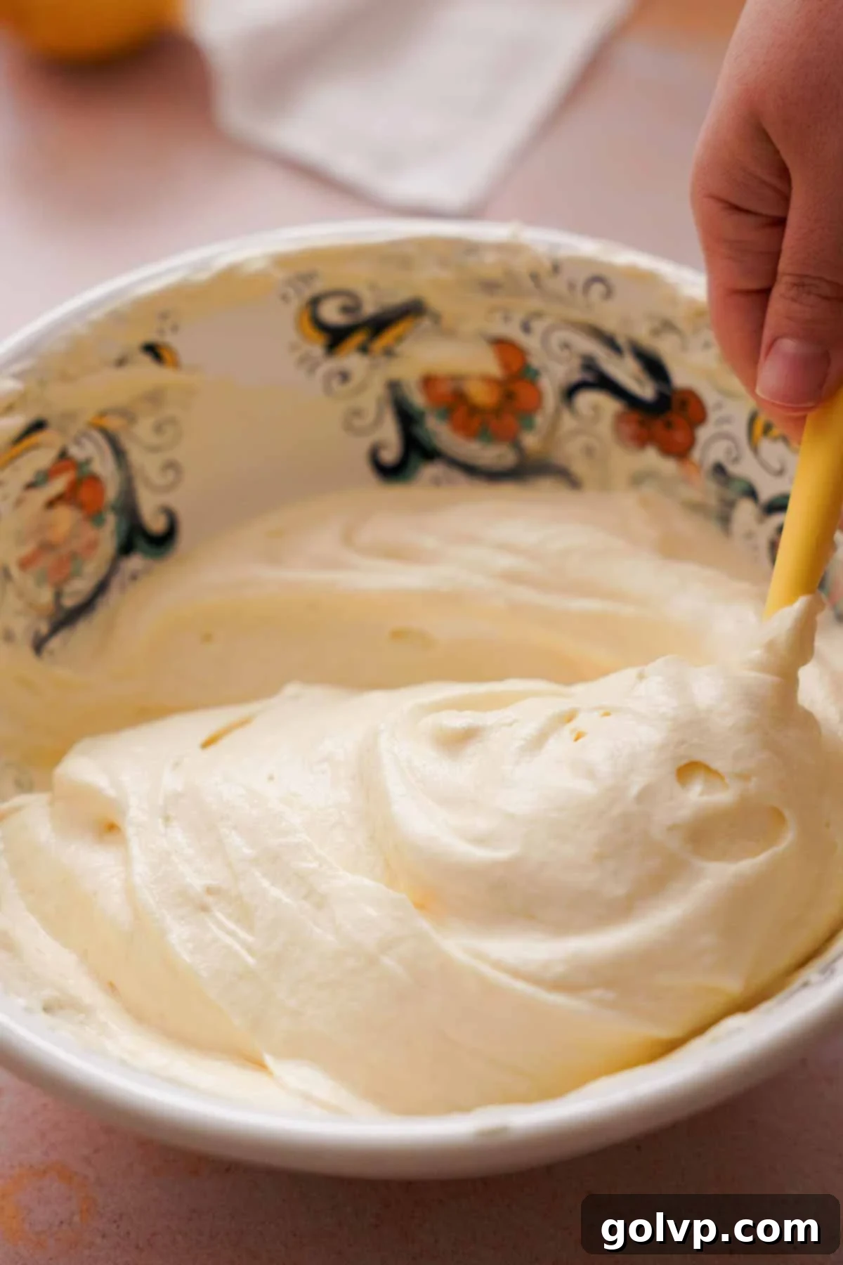 Carefully folding whipped cream into the lemon mousse mixture in a large serving bowl.