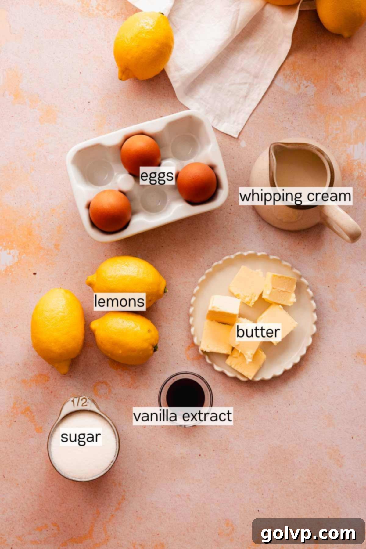 Various ingredients for lemon mousse, including fresh lemons, eggs, butter, and cream, displayed in small dishes on a counter.