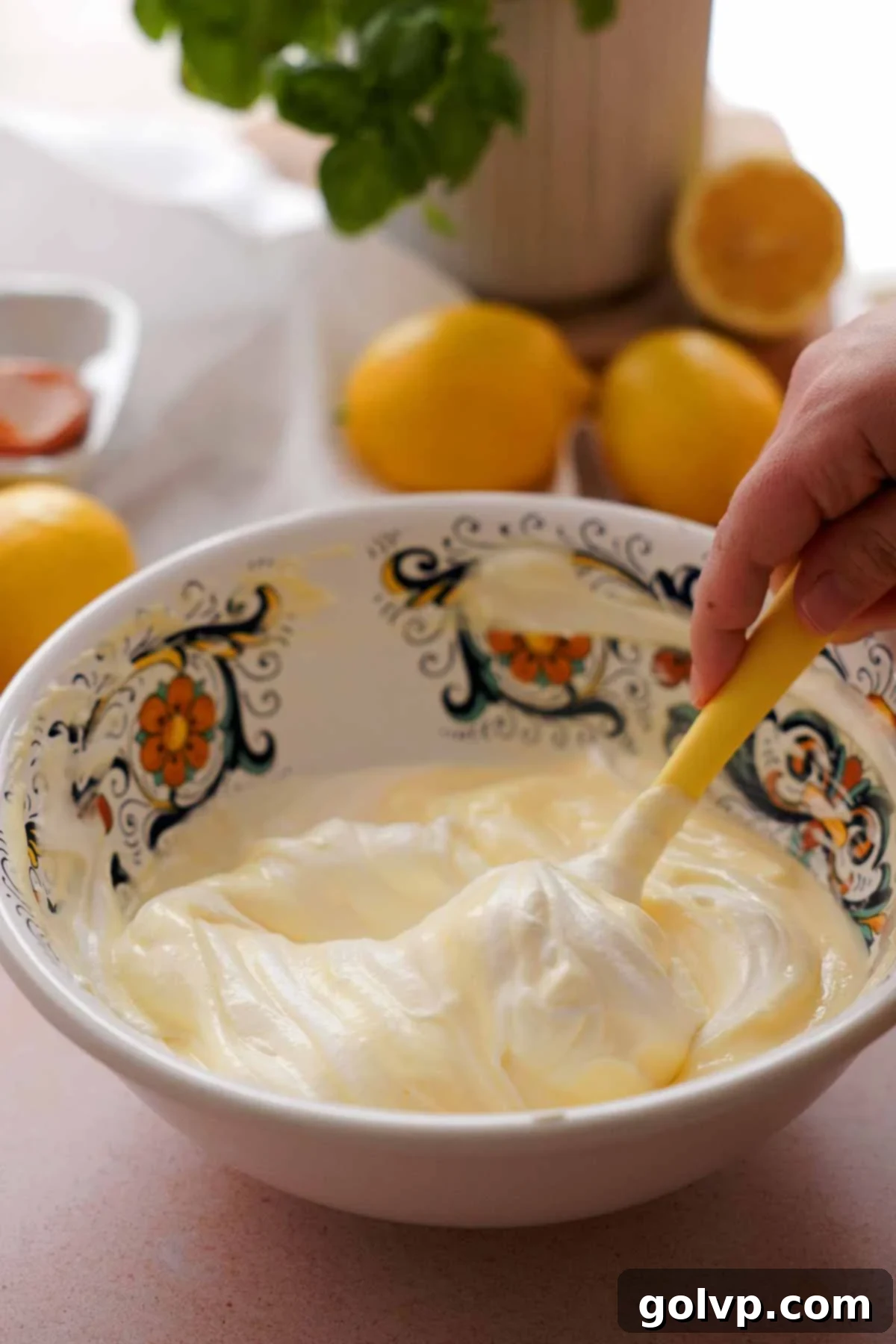 Gently folding fluffy Swiss meringue into the cooled lemon curd mixture in a large serving bowl.