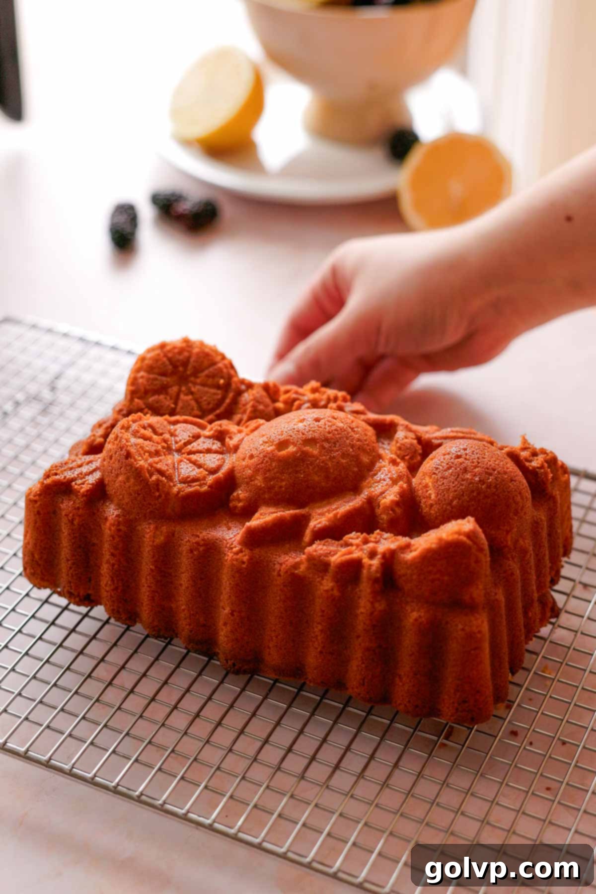 baked lemon pound cake cooling on a wire rack outside of the pan