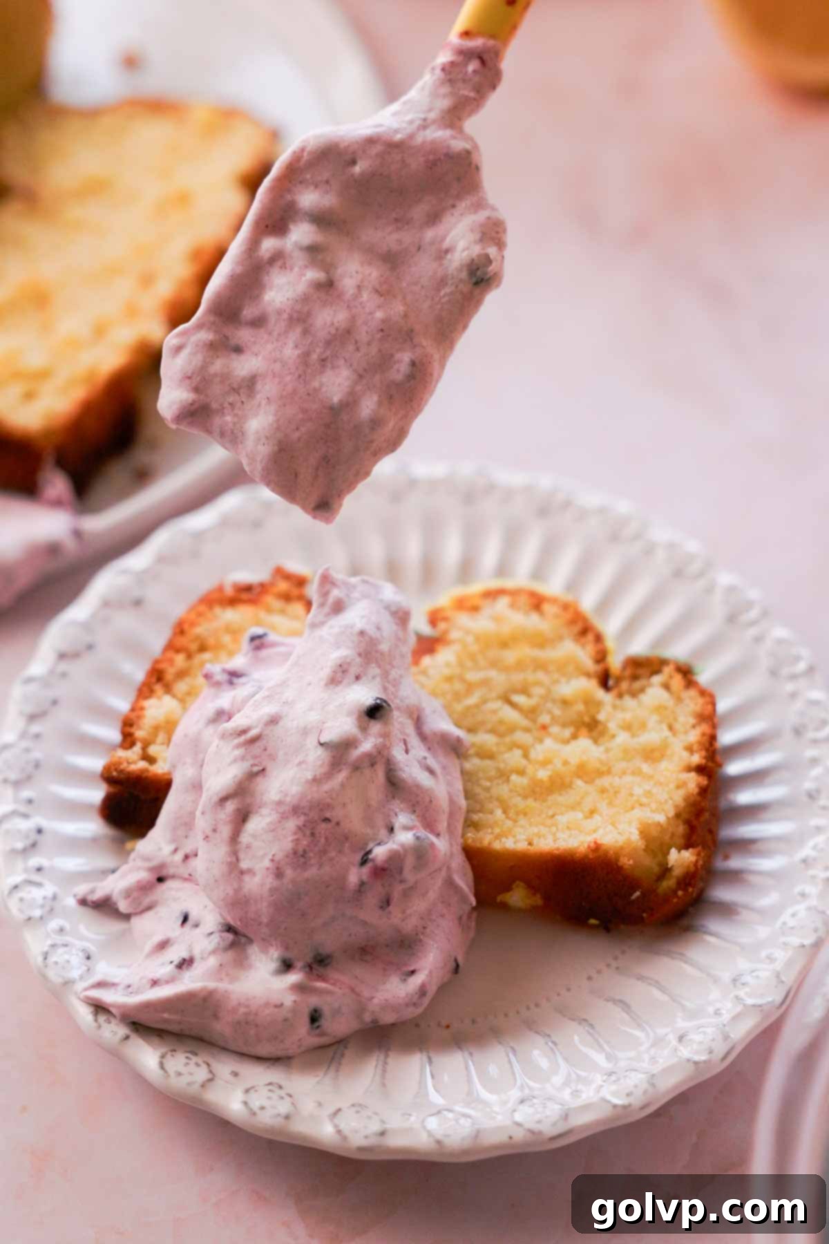 thick slice of lemon pound cake topped with generous scoops of blackberry whipped cream and fresh berries