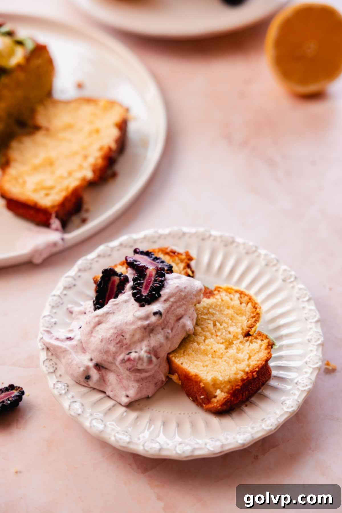 slice of lemon pound cake with generous dollop of blackberry whipped cream and fresh blackberries