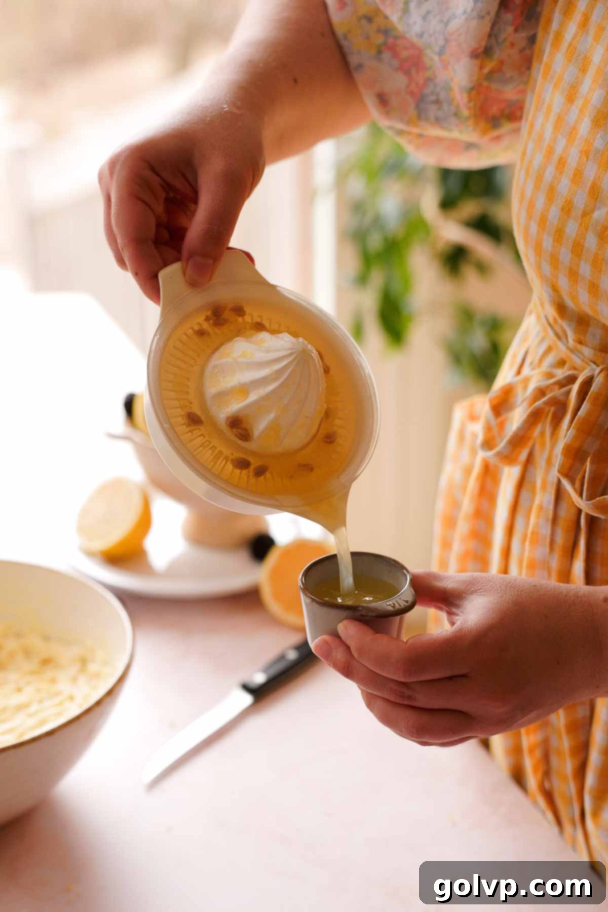 pouring measured lemon juice into a bowl, next to a bowl of Greek yogurt
