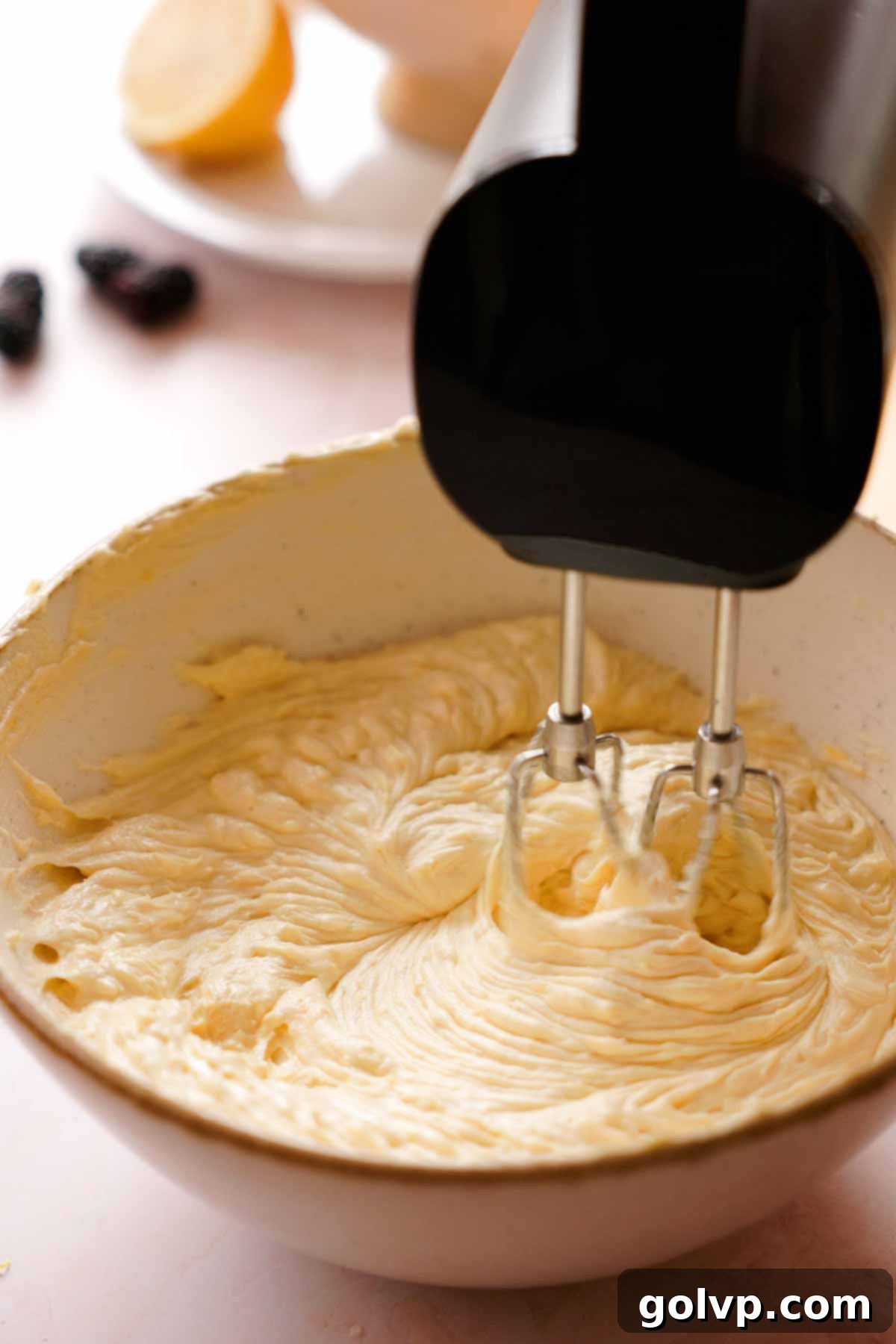creaming lemon pound cake batter in a large bowl with an electric mixer after adding dry ingredients