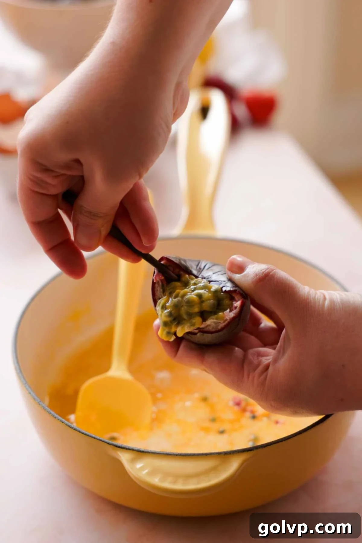 scooping passion fruit seeds into saucepan with curd
