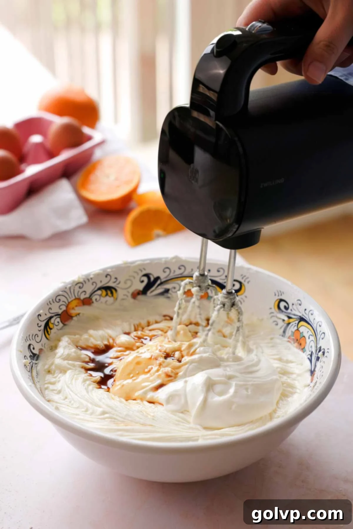 mixing cheesecake batter with sour cream and vanilla with an electric hand mixer
