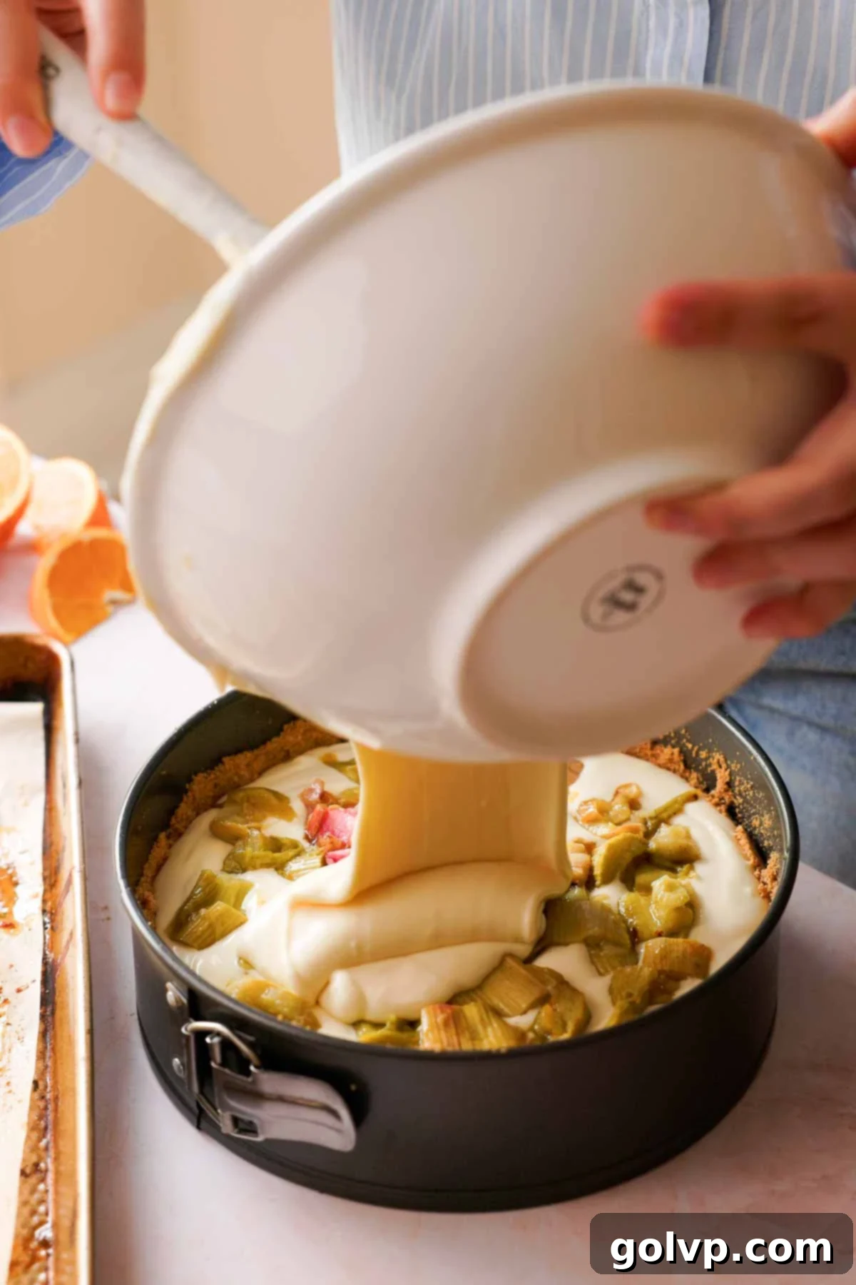 pouring cheesecake batter over layer of roast rhubarb