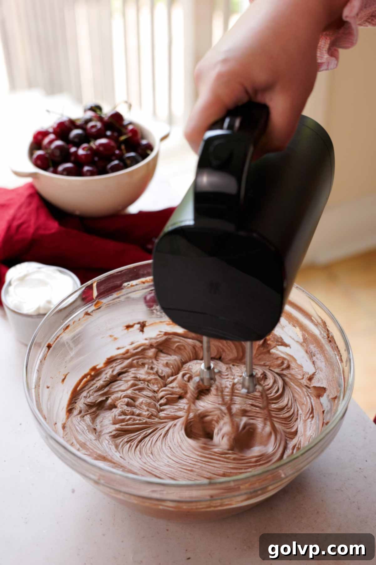 mixing cream cheese, sugar, and cocoa powder with electric mixer in large glass bowl